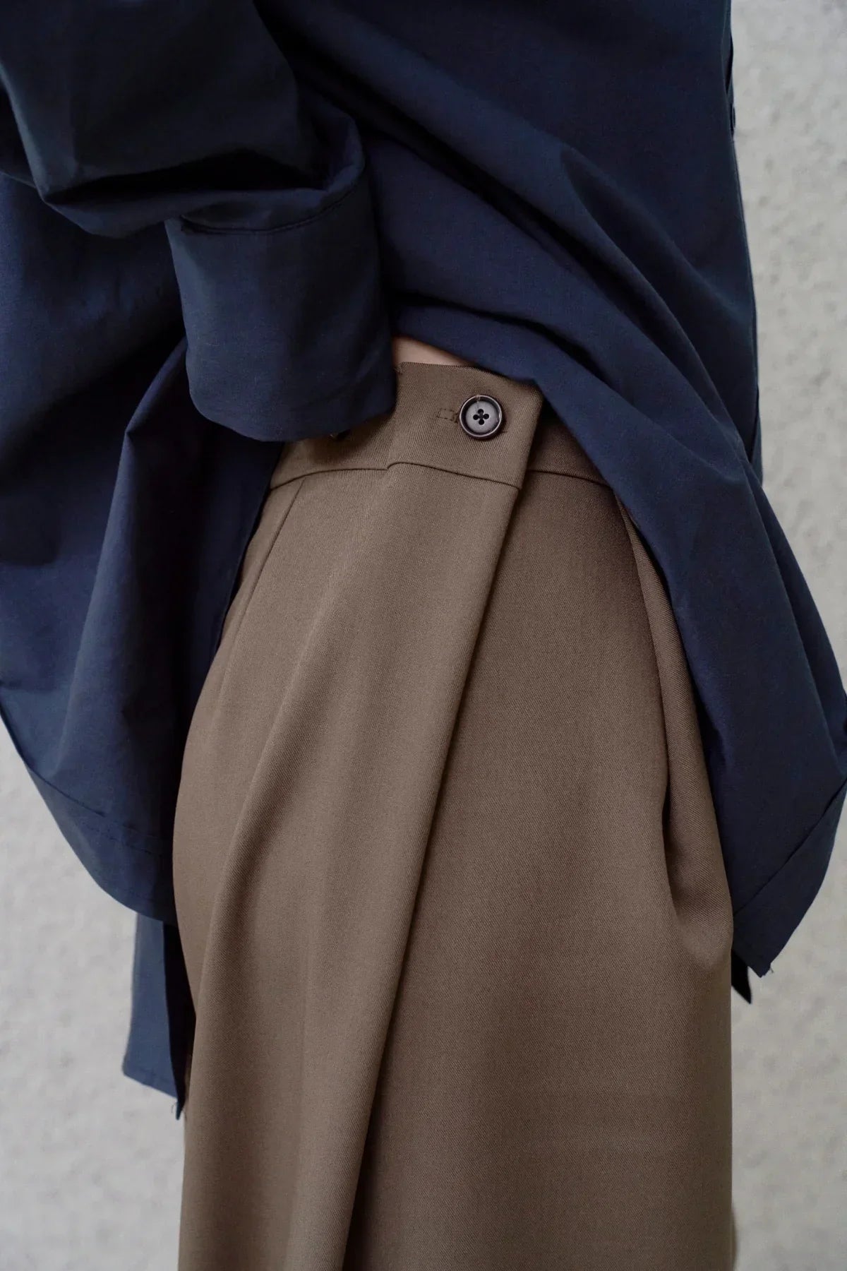 Close-up of wide-fit brown pants with button detail paired with navy blue shirt