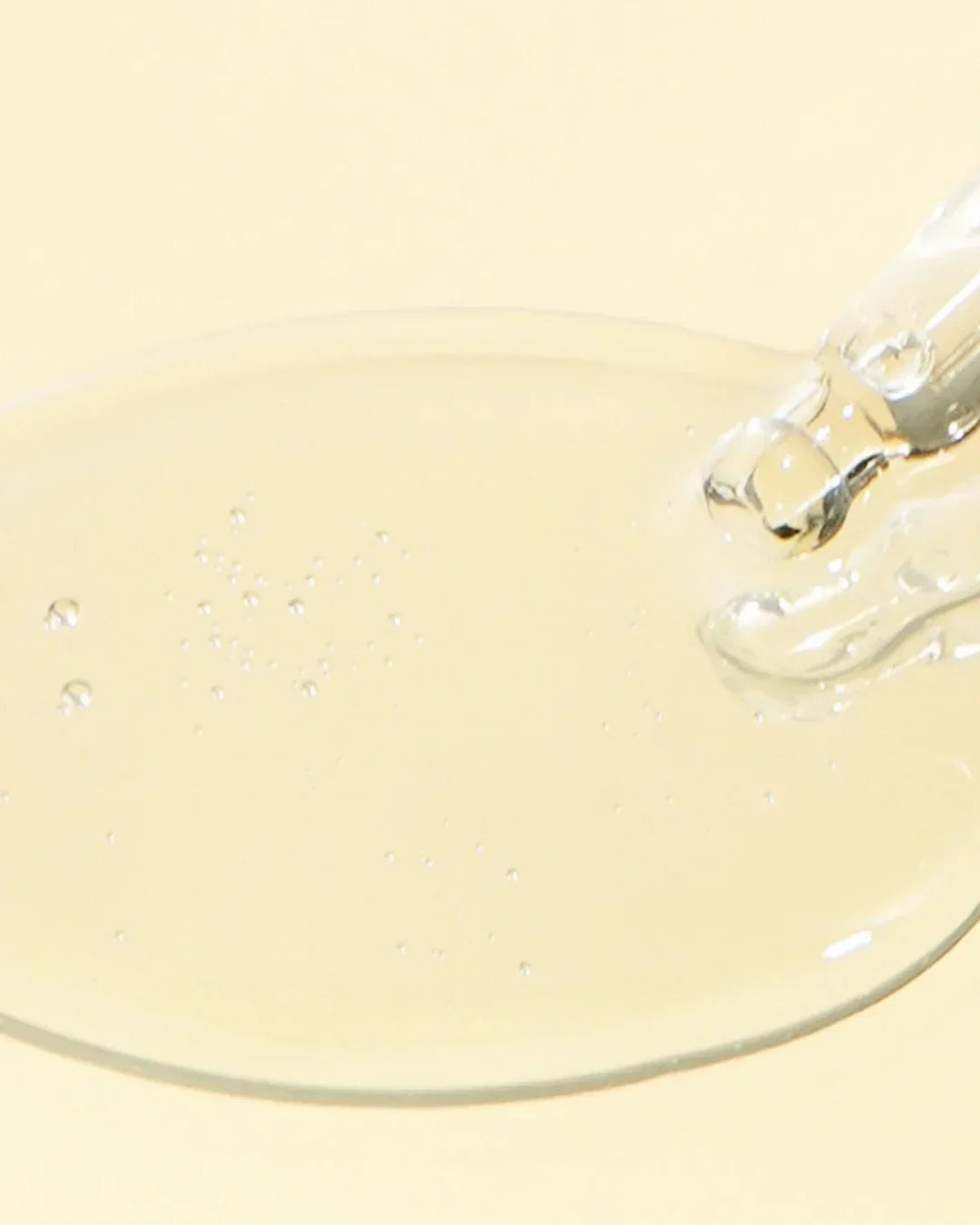 Clear niacinamide serum texture with bubbles on pale yellow background