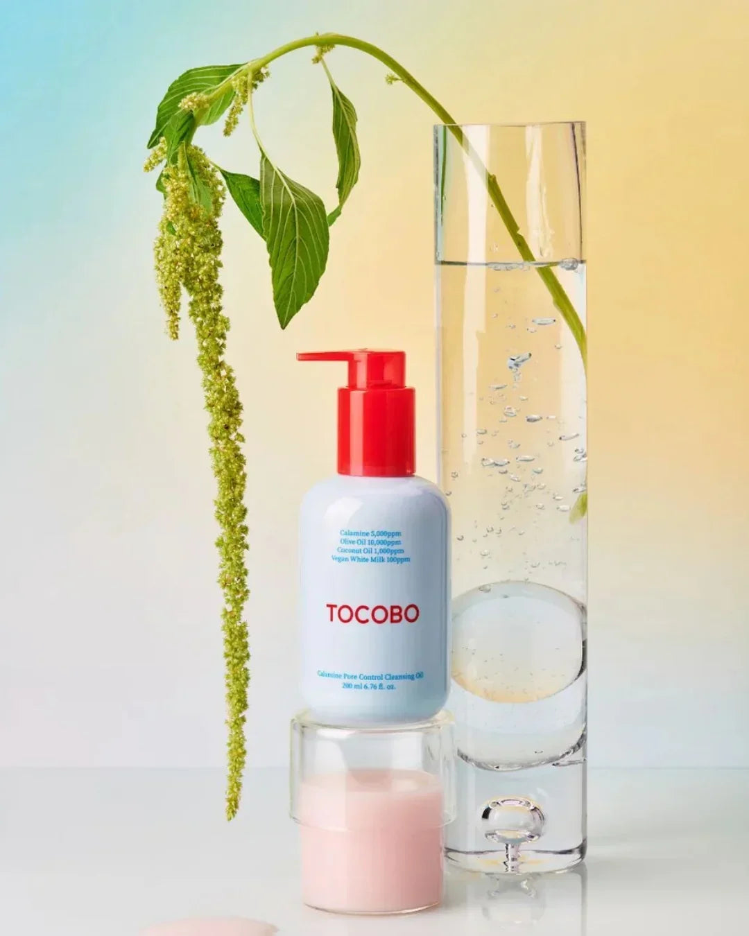 TOCOBO Calamine pore control cleansing oil with red pump beside a tall glass vase with green plant