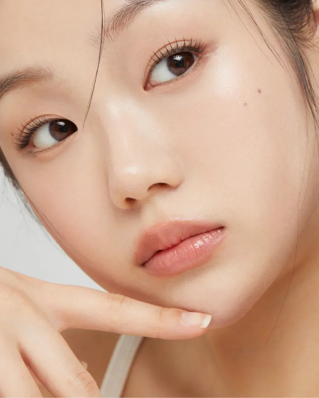 Close-up of a woman with clear, glowing skin and natural makeup highlighting fresh, healthy complexion