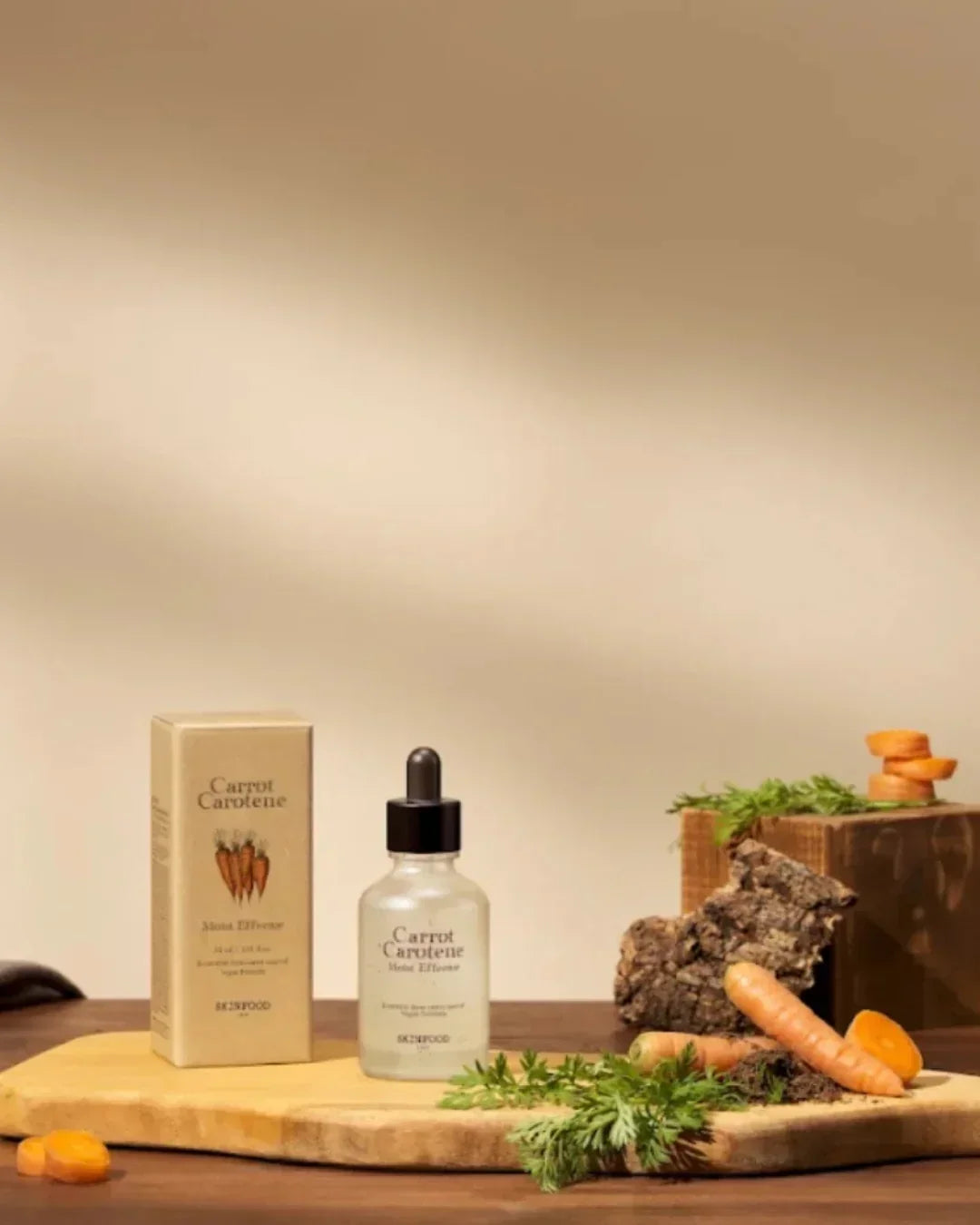 Carrot Carotene Moist Effector serum bottle with box on wooden board, fresh carrots and greenery