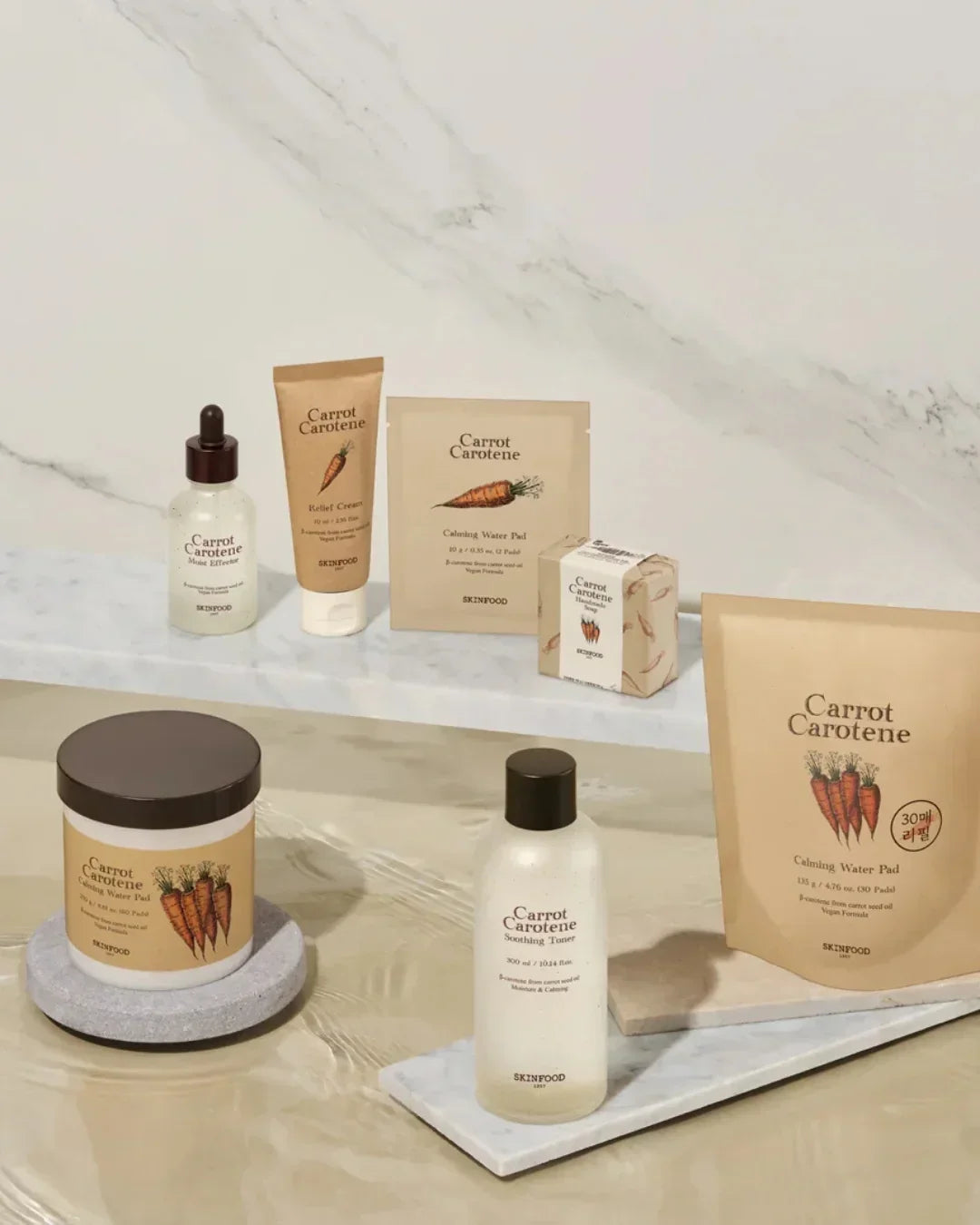 Skinfood Carrot Carotene skincare set including cream, toner, water pads, and serum on marble surfaces