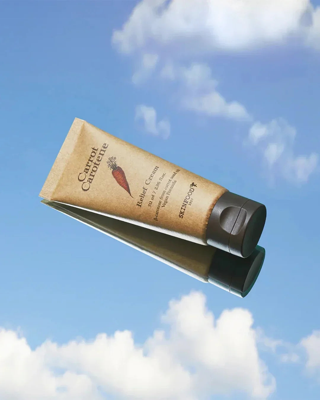 Carrot Carotene Relief Cream 70ml tube by Skinfood against a blue sky with clouds