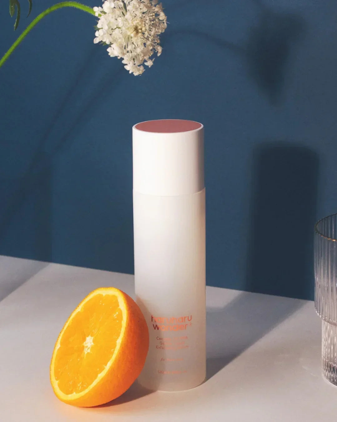 HaruHaru Wonder Centella 3-PHA Gentle Liquid Exfoliating Serum bottle with half orange on white surface