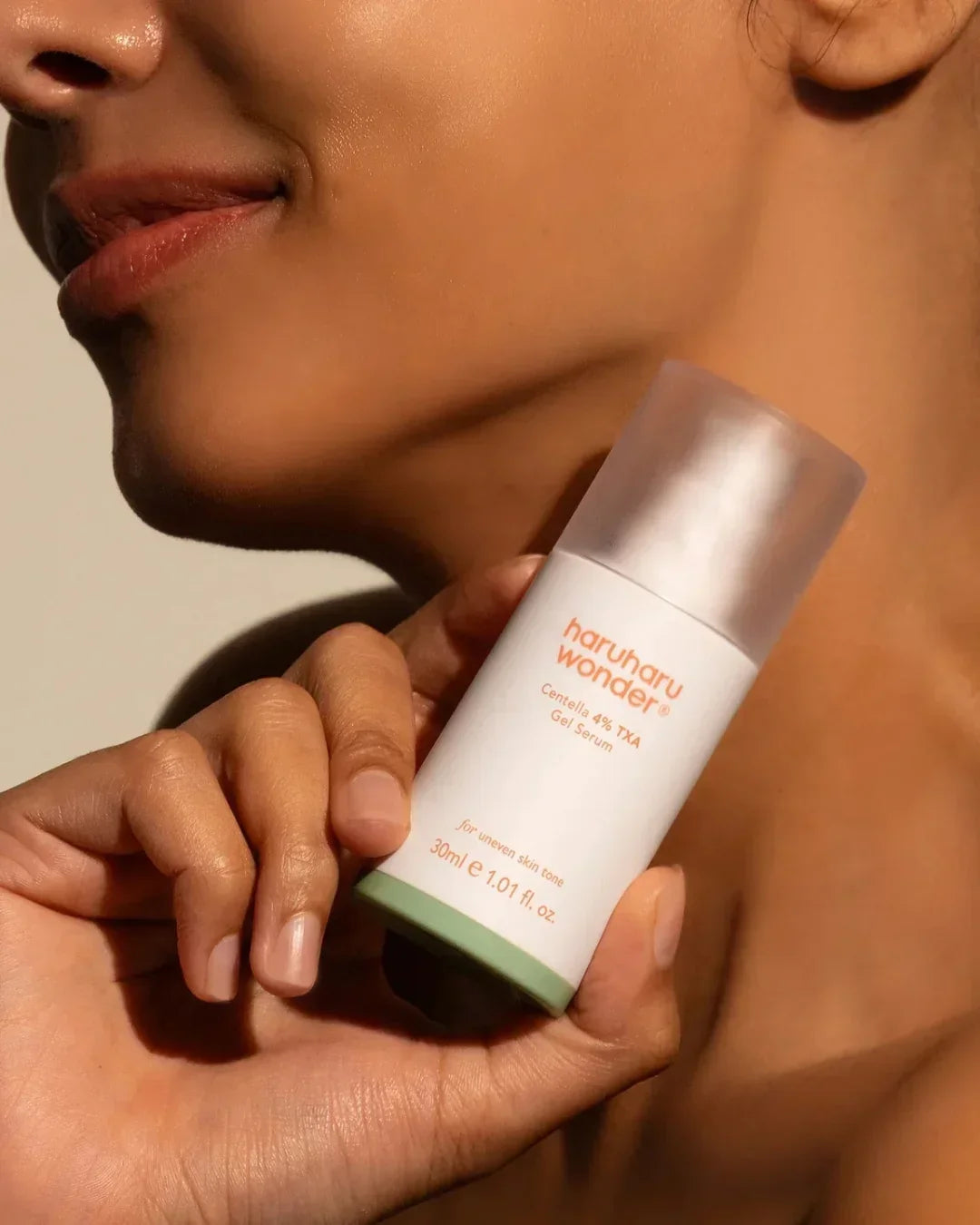 Close-up of a person holding Haruharu Wonder Centella 4% TXA Gel Serum bottle near their face