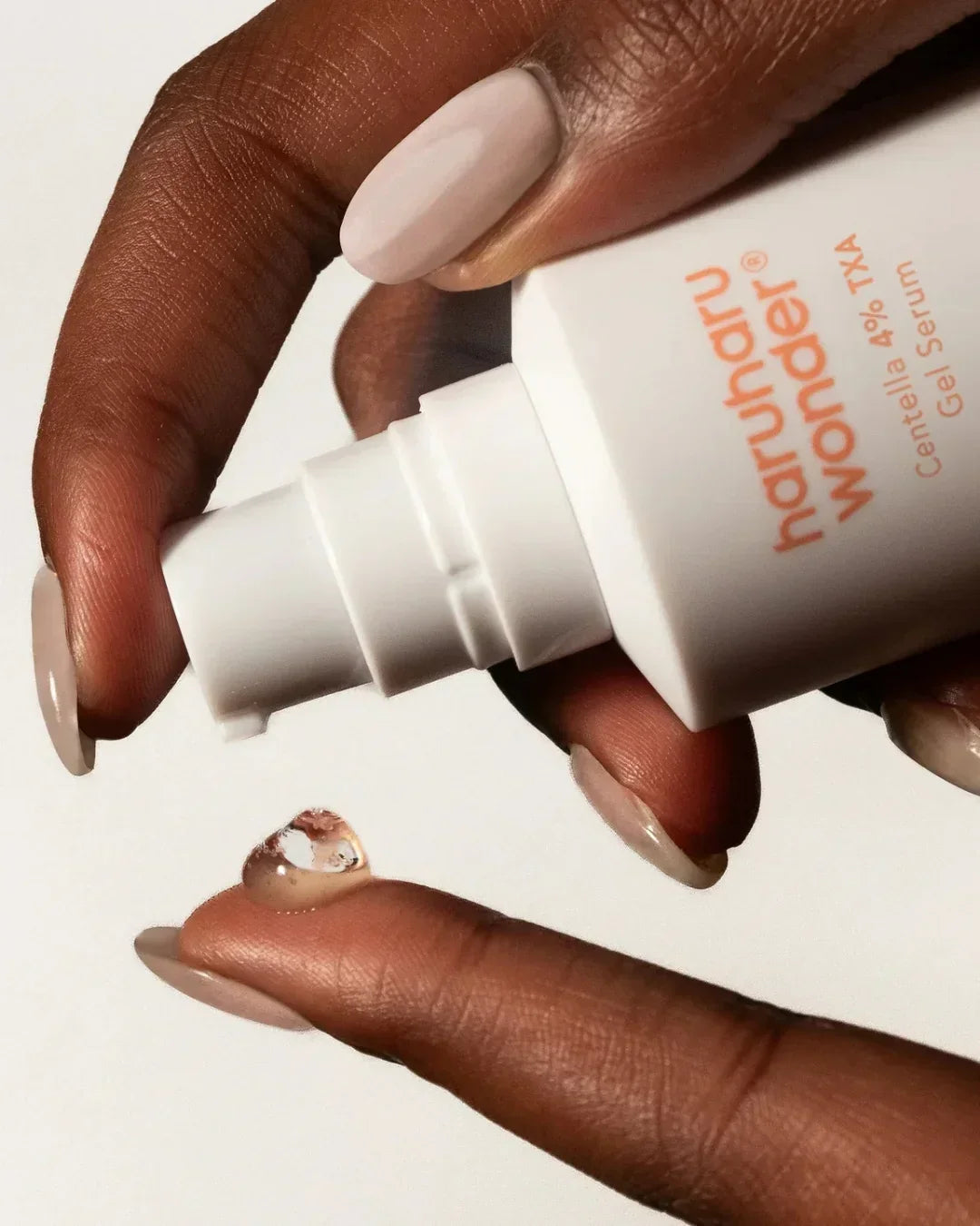 Hand with nude nail polish dispensing Haruharu Wonder Centella 4% TXA gel serum drop