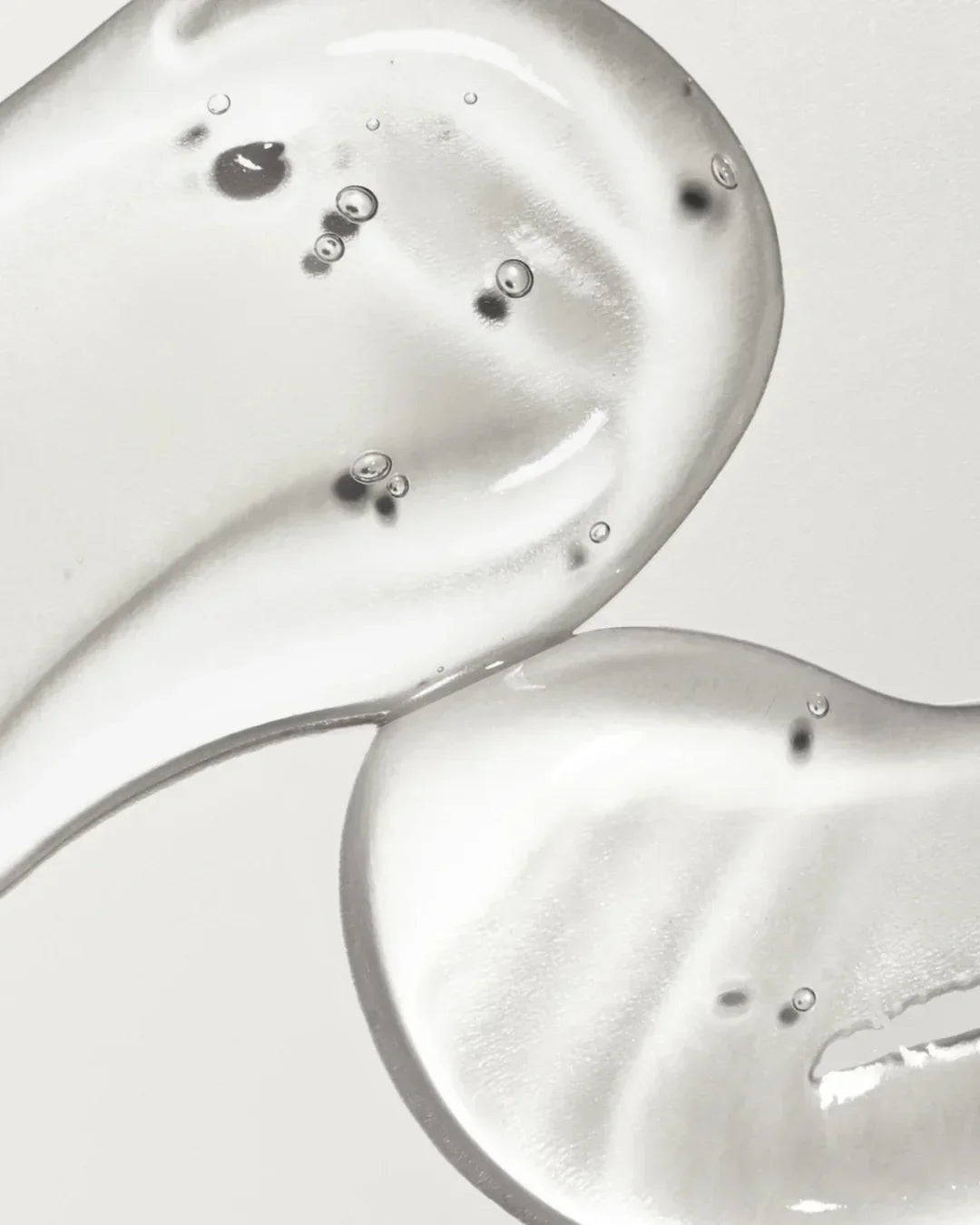 Clear gel serum texture with air bubbles on a light background, showing smooth skincare product