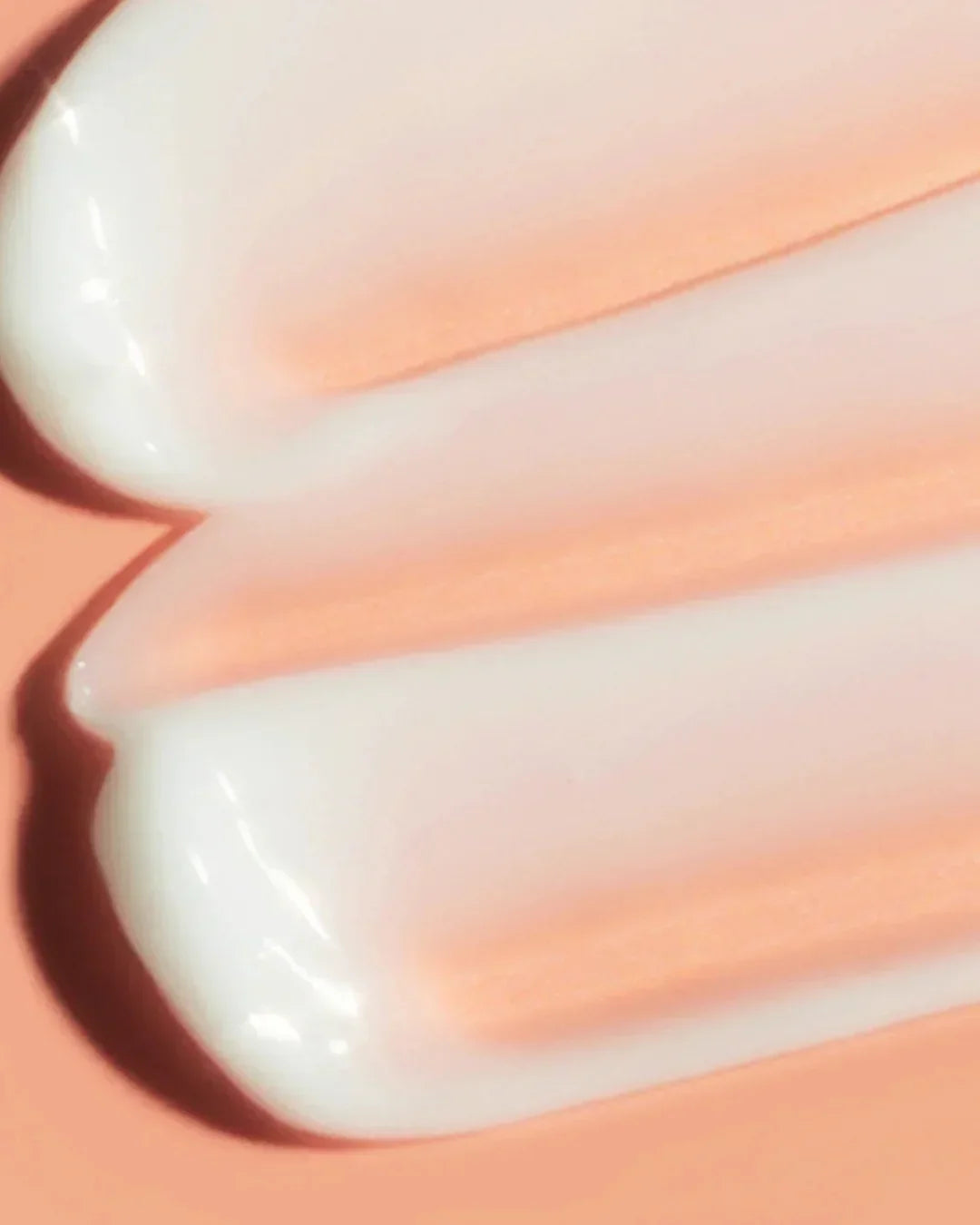 Texture of creamy white radiance gel cream on peach background