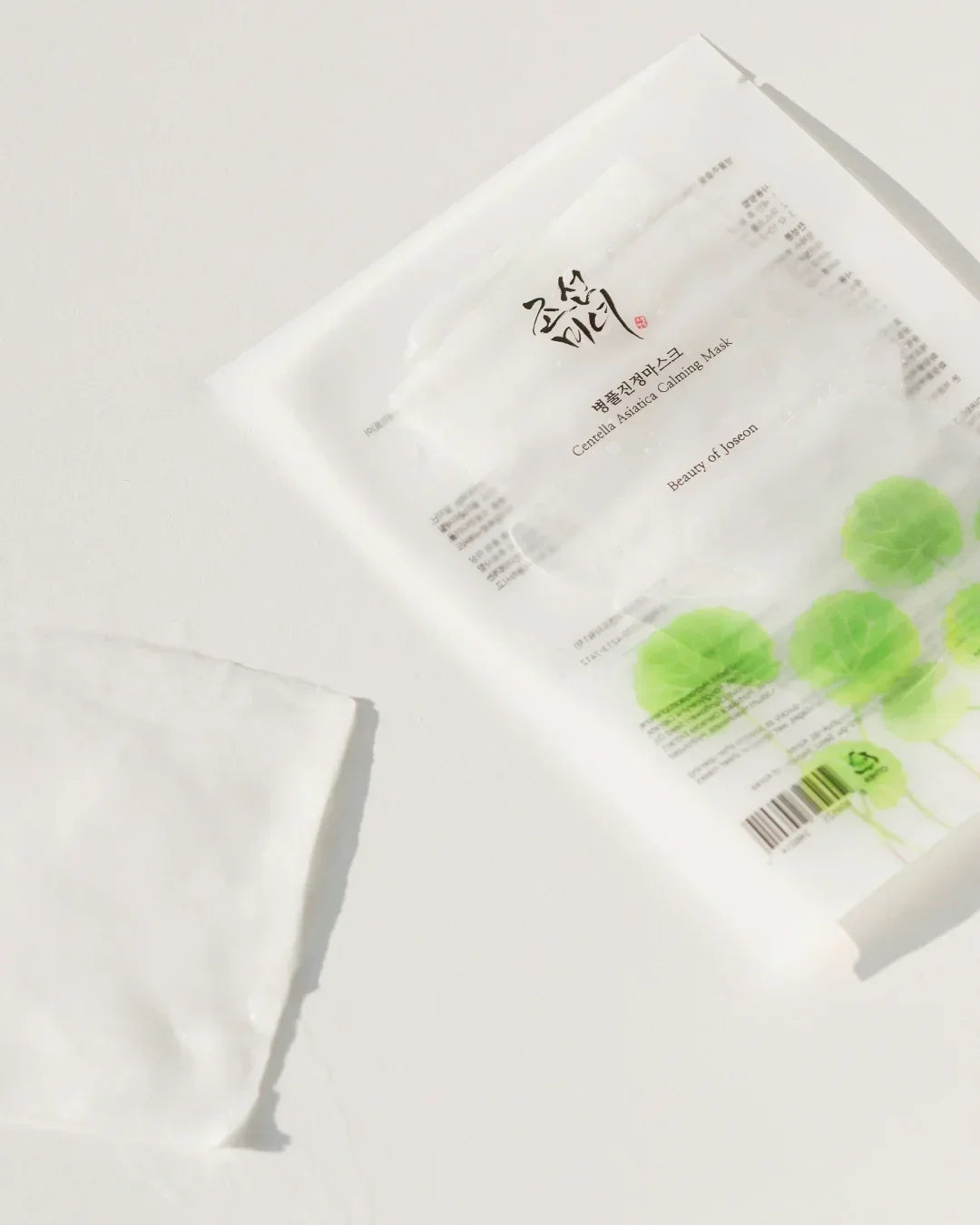 Centella Asiatica Calming Mask packaging with green leaf design and sheet mask on white surface