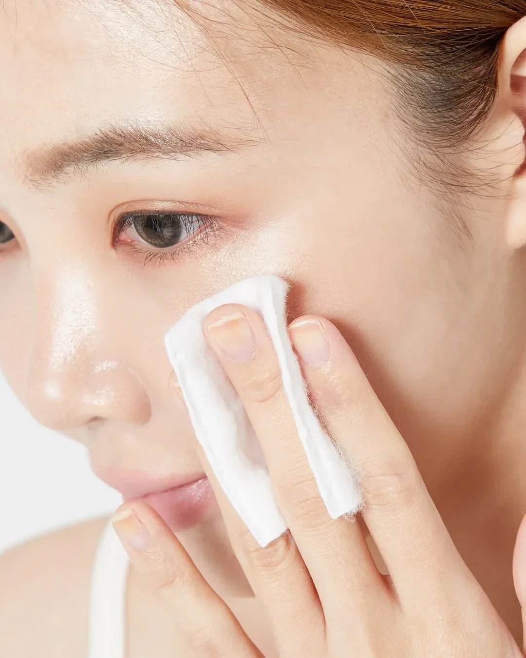 Close-up of woman gently cleansing face with cotton pad for skincare routine