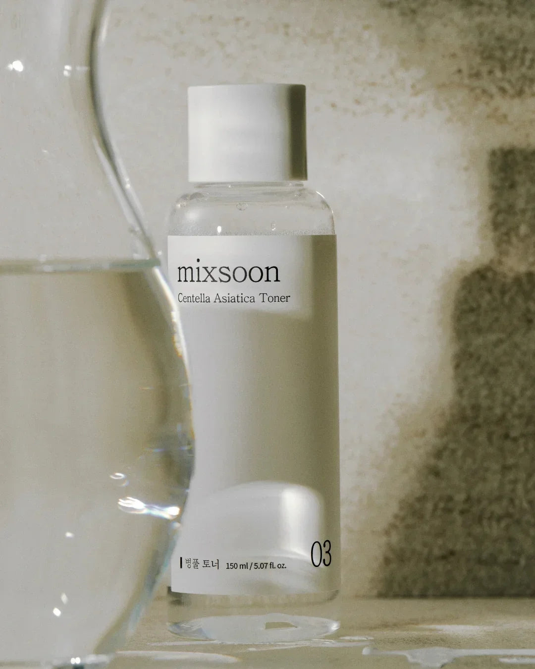 Mixsoon Centella Asiatica Toner bottle 150ml on textured surface with glass water in foreground