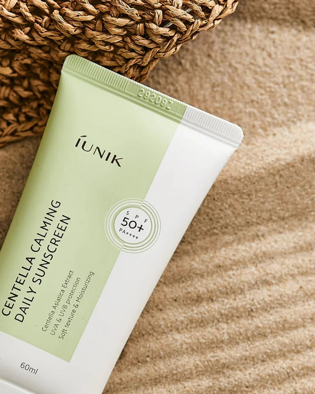 IUNIK Centella Calming Daily Sunscreen SPF 50+ PA++++ tube on textured beige surface with woven decor