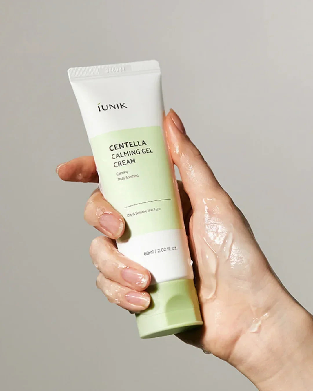 Hand holding iUNIK Centella Calming Gel Cream tube with clear gel on skin, skincare product