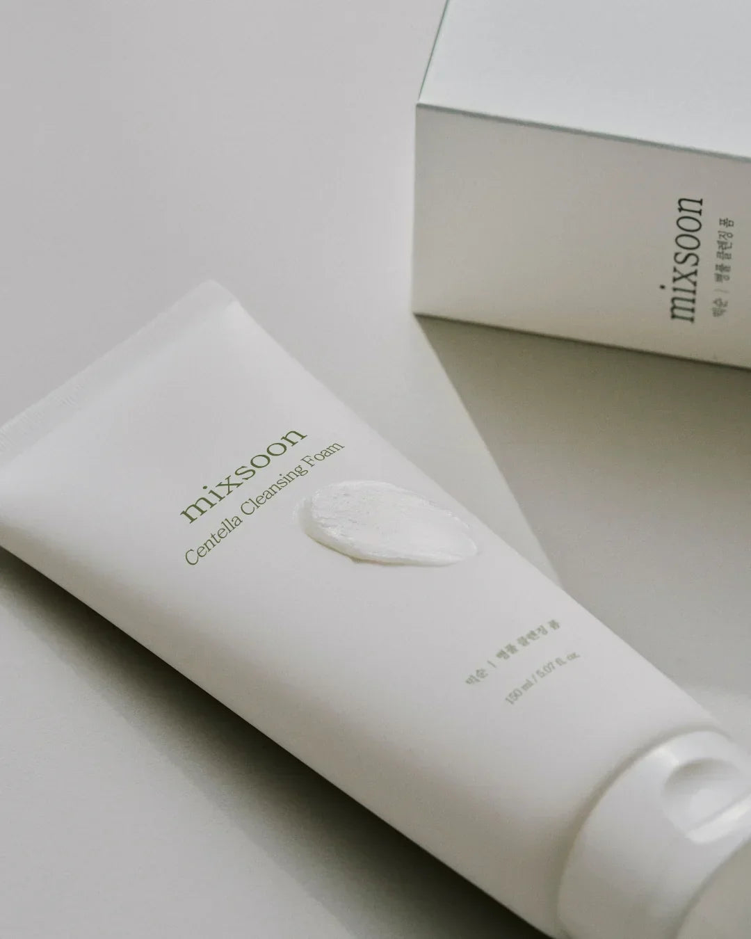Mixsoon Centella Cleansing Foam tube with cream texture and matching product box on neutral surface