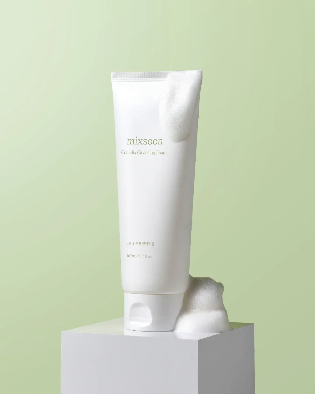 Mixsoon Centella Cleansing Foam tube with white foam on minimal green background