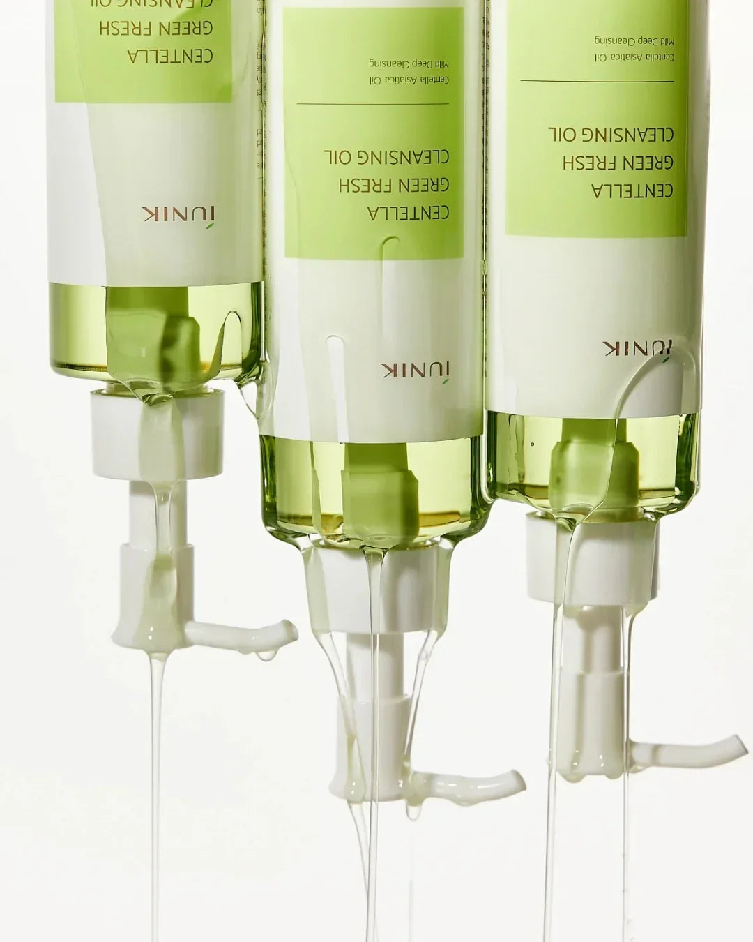 Three tubes of IUNIK Centella Green Fresh Cleansing Oil with transparent oil dripping from white pumps