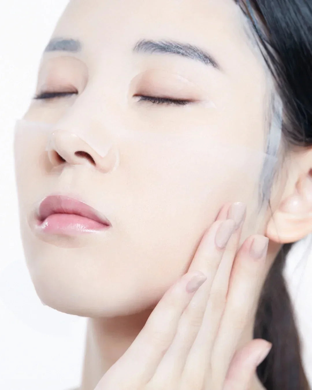 Close-up of woman applying transparent hydrogel eye patches and touching her cheek for skincare
