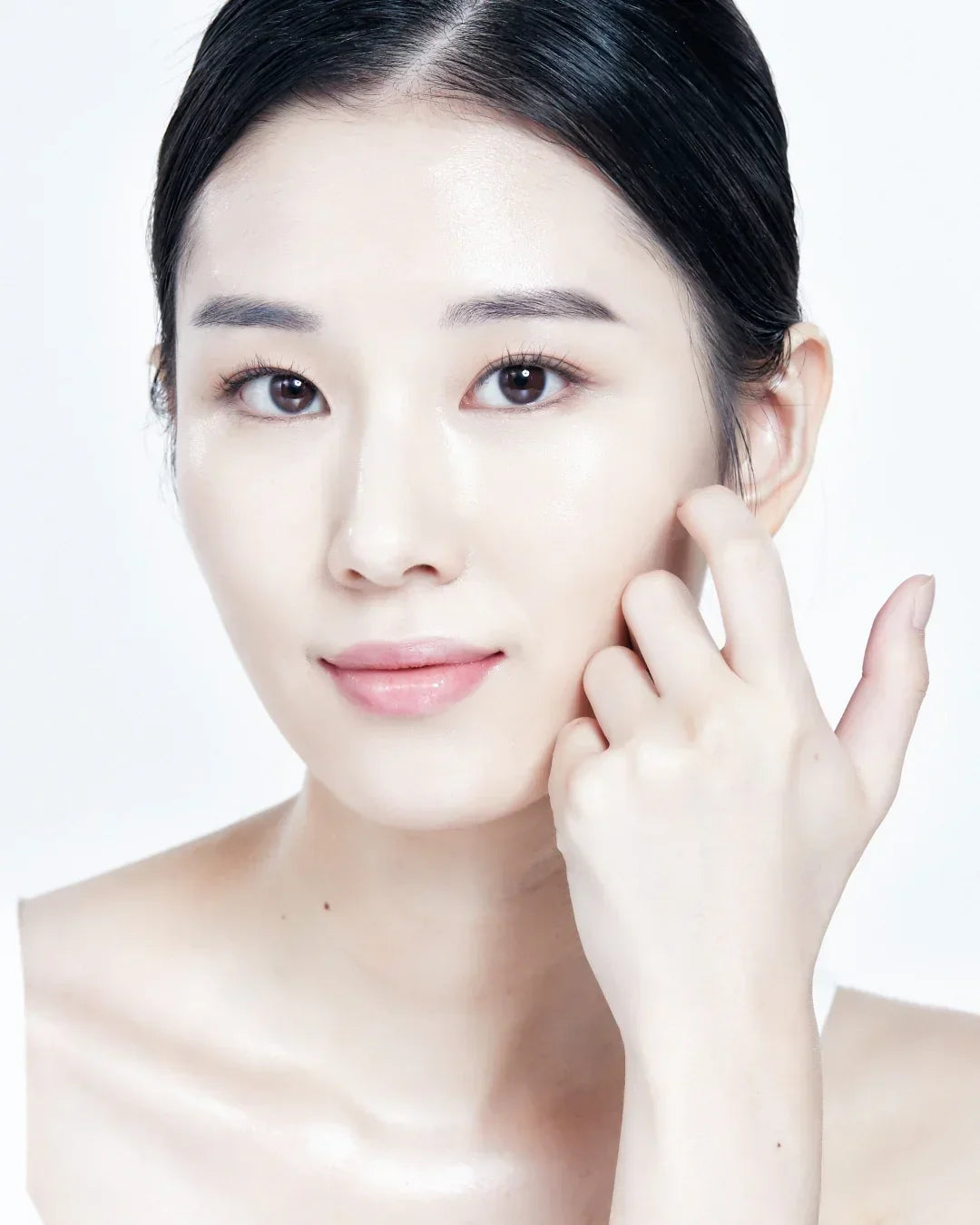 Close-up of woman with clear glowing skin gently touching her cheek, skincare beauty concept