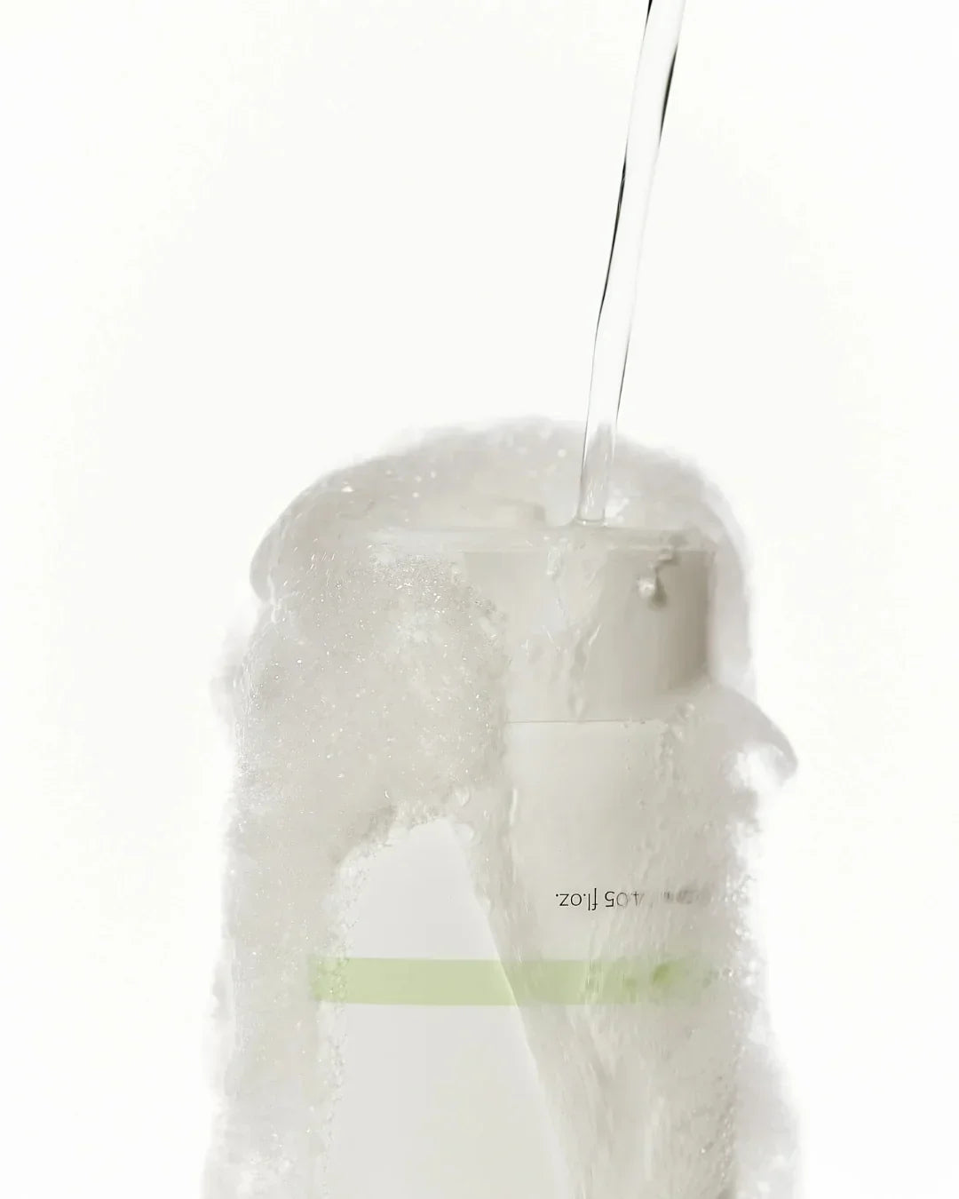 Close-up of Centella Mild Cleansing Foam bottle top with water pouring and foam overflow