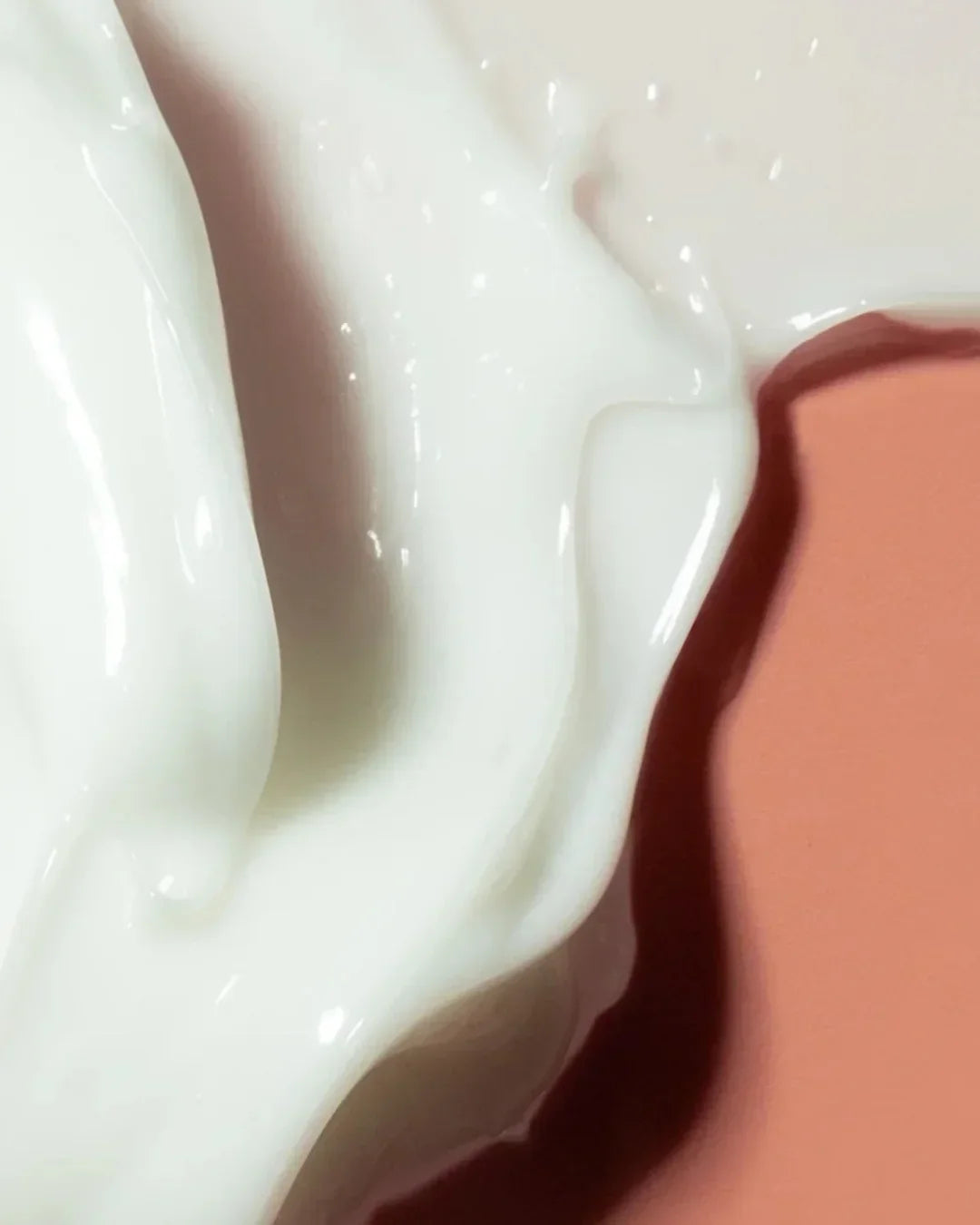 close-up of creamy white skincare product texture on peach background