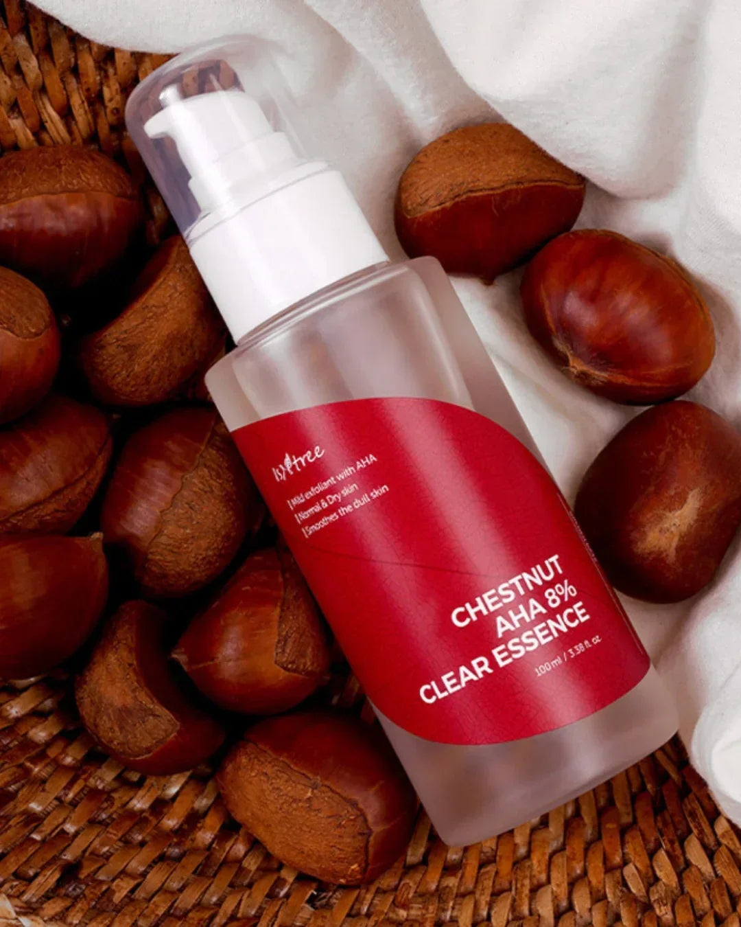Chestnut AHA 8% Clear Essence skincare bottle on wicker basket with chestnuts and white cloth