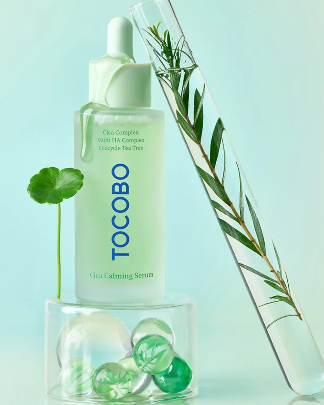 Tocobo Cica Calming Serum bottle with dropper, green leaf, and test tube with plant inside