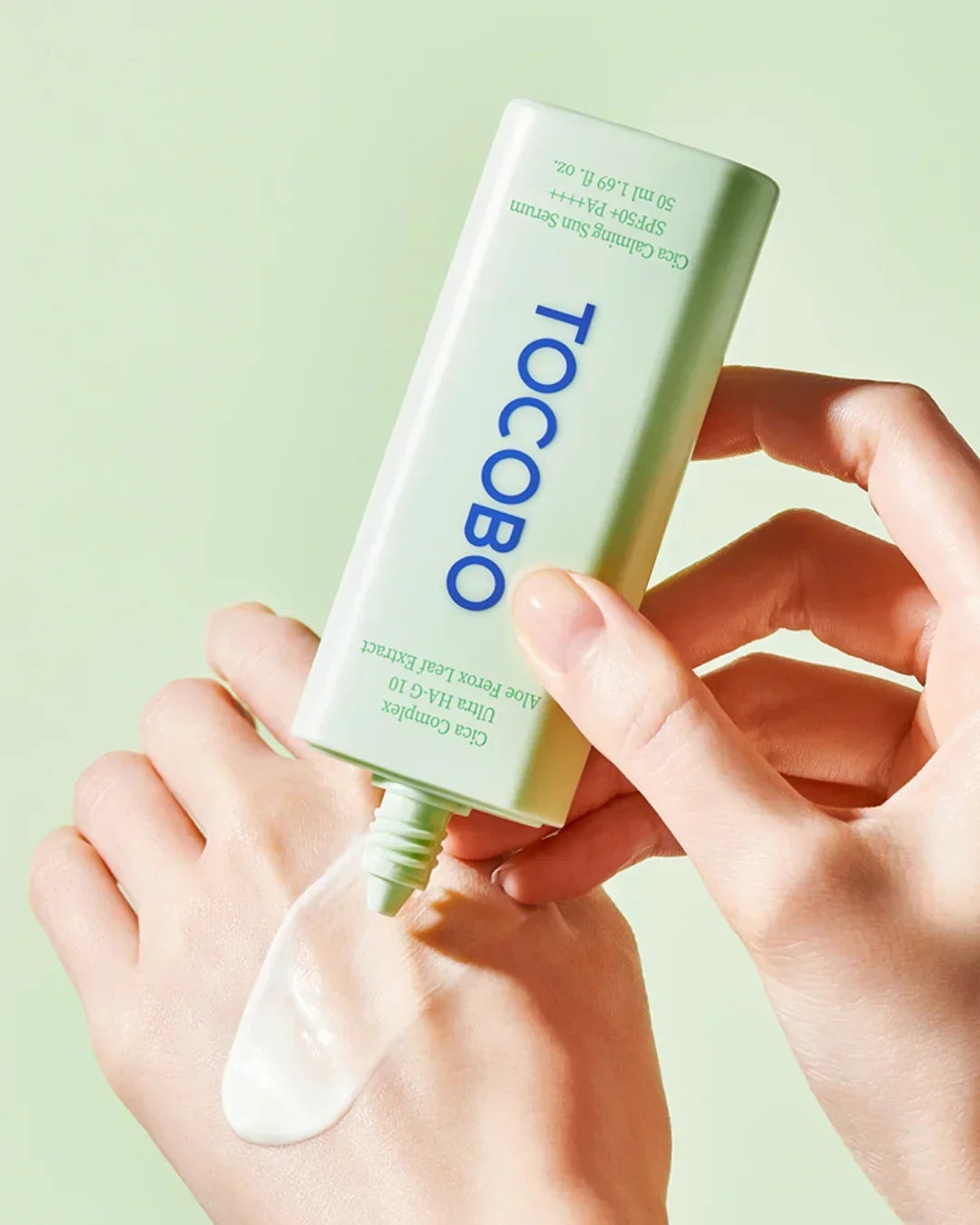 Hand dispensing Tocobo Cica Calming Sun Serum SPF50 PA++++ sunscreen lotion on skin