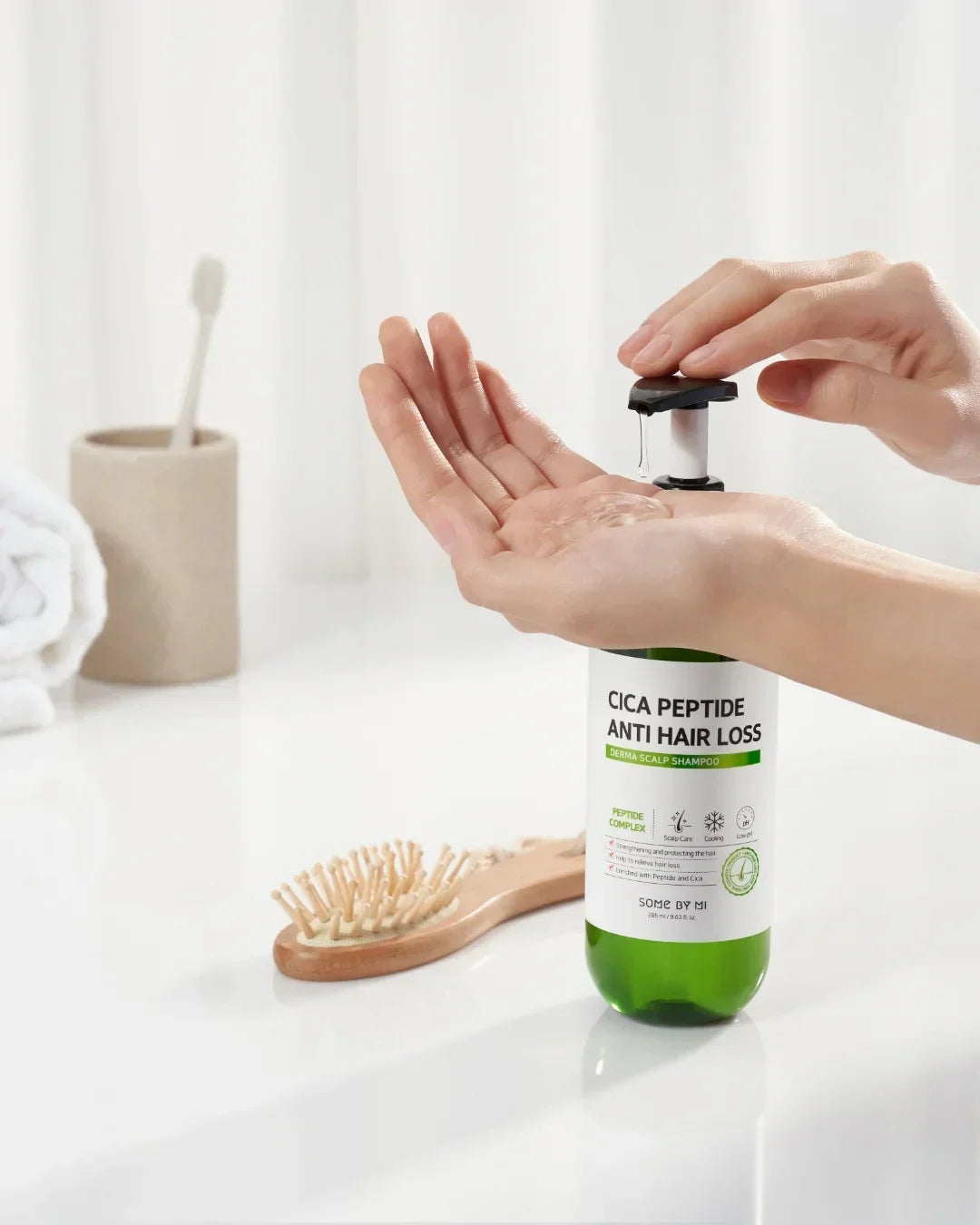 Dispensing Cica Peptide Anti Hair Loss Derma Scalp Shampoo on hand with hairbrush and towel