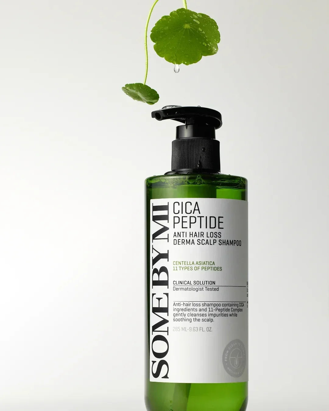 Green bottle of SOMEBYMI Cica Peptide anti hair loss derma scalp shampoo with water droplets and green leaves