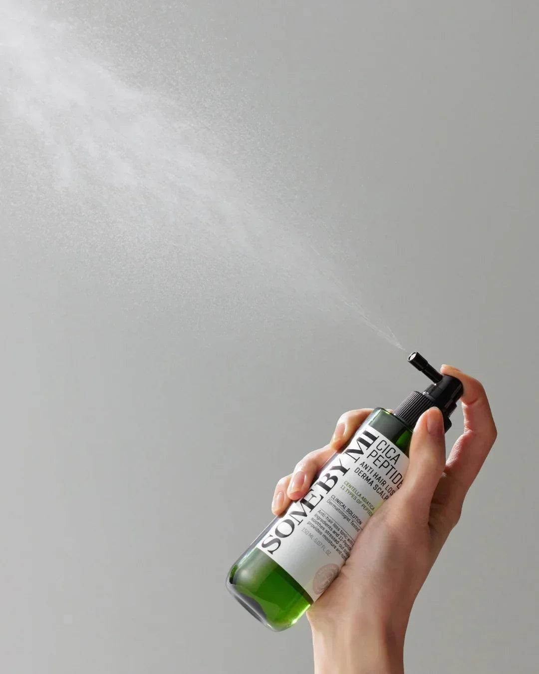 Hand spraying SOMEBYMI Cica Peptide Anti Hair Loss Derma Scalp Tonic spray