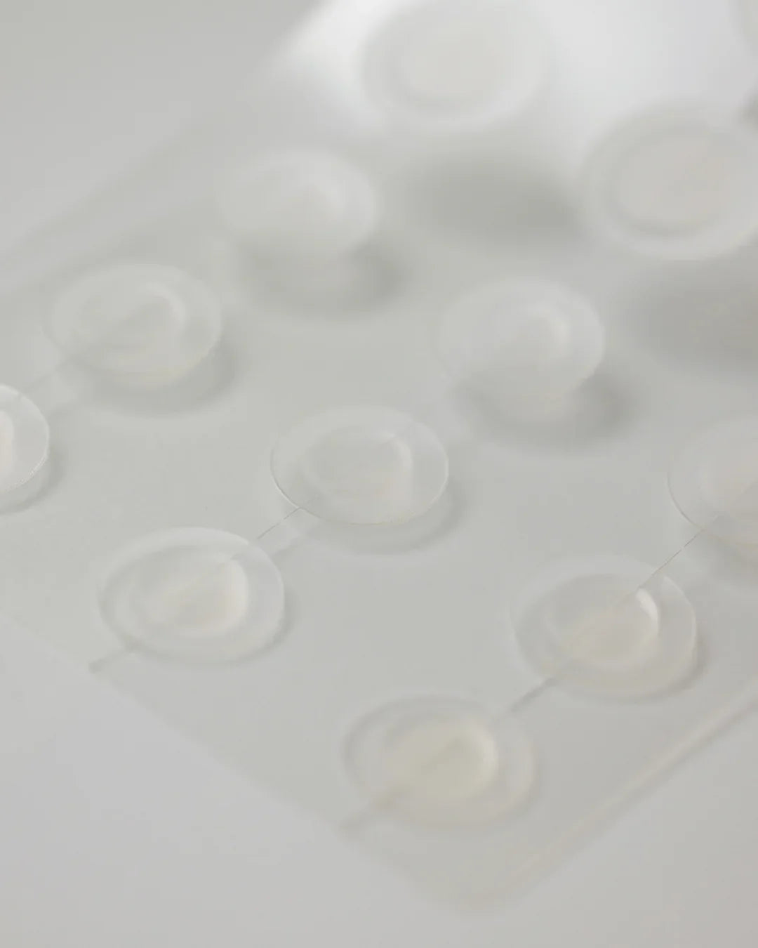 Close-up of transparent clear spot patches arranged in a grid on a white surface