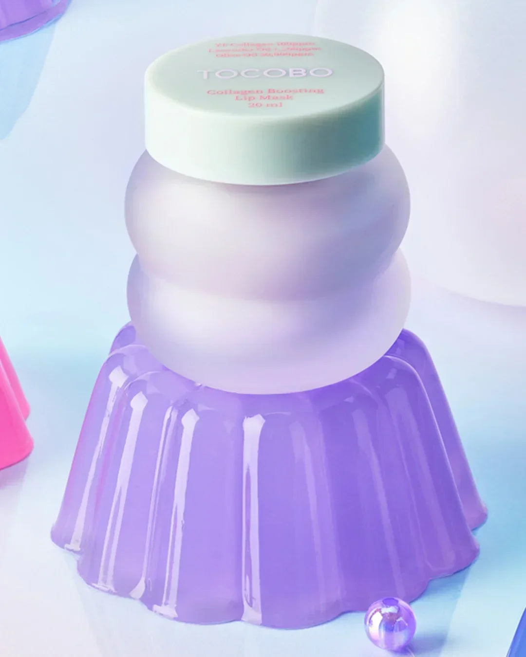 Tocobo Collagen Boosting Lip Mask jar on a purple gelatin-like stand with soft pastel background