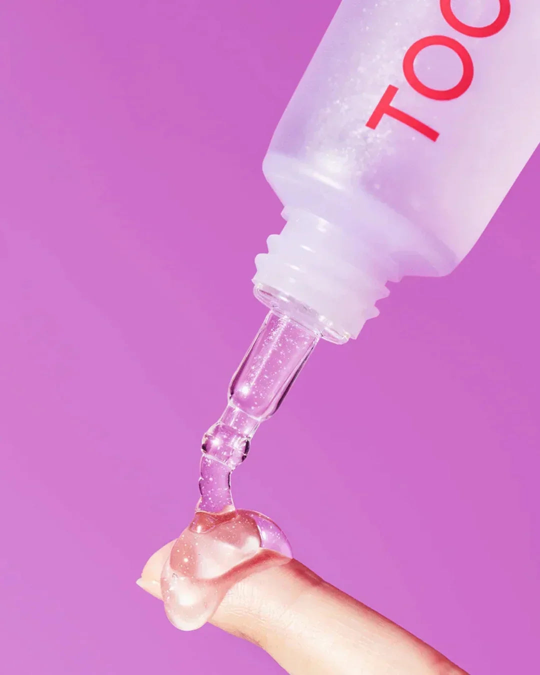 Clear collagen brightening eye gel being dispensed on finger with pink background
