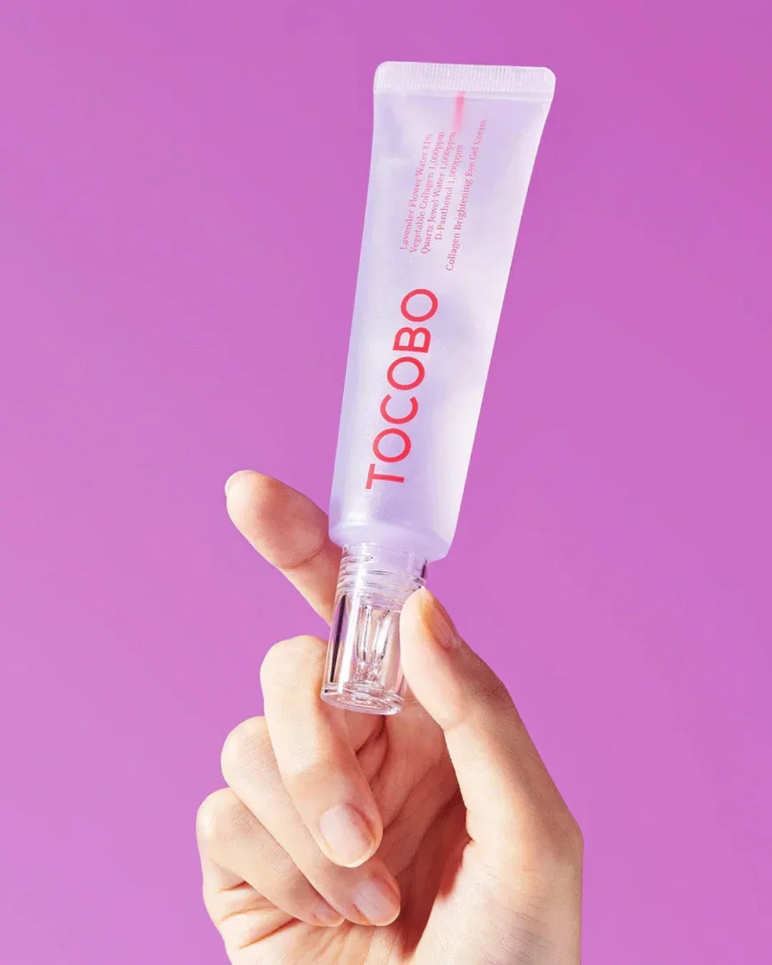Hand holding TOCOBO collagen brightening eye gel cream tube against purple background