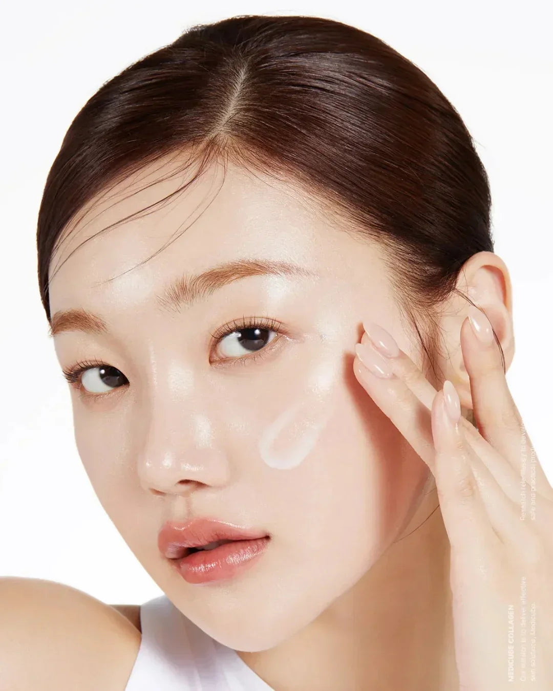 Close-up of woman applying collagen glow booster serum on glowing skin