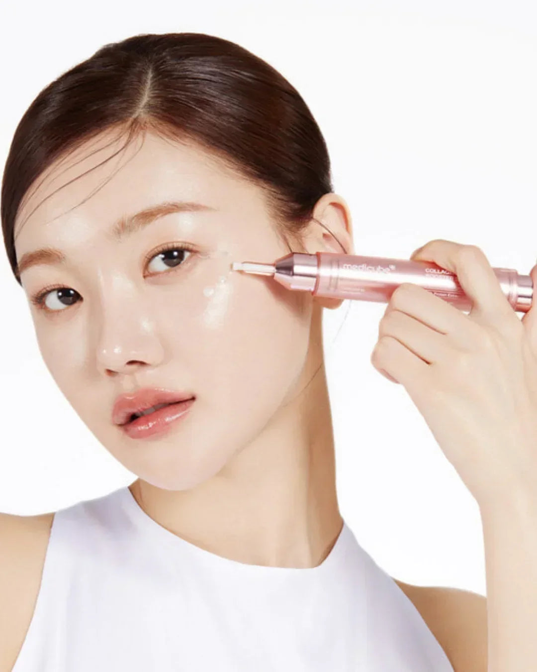 Young woman applying Mediciube Collagen Glow Booster serum near eye on glowing skin
