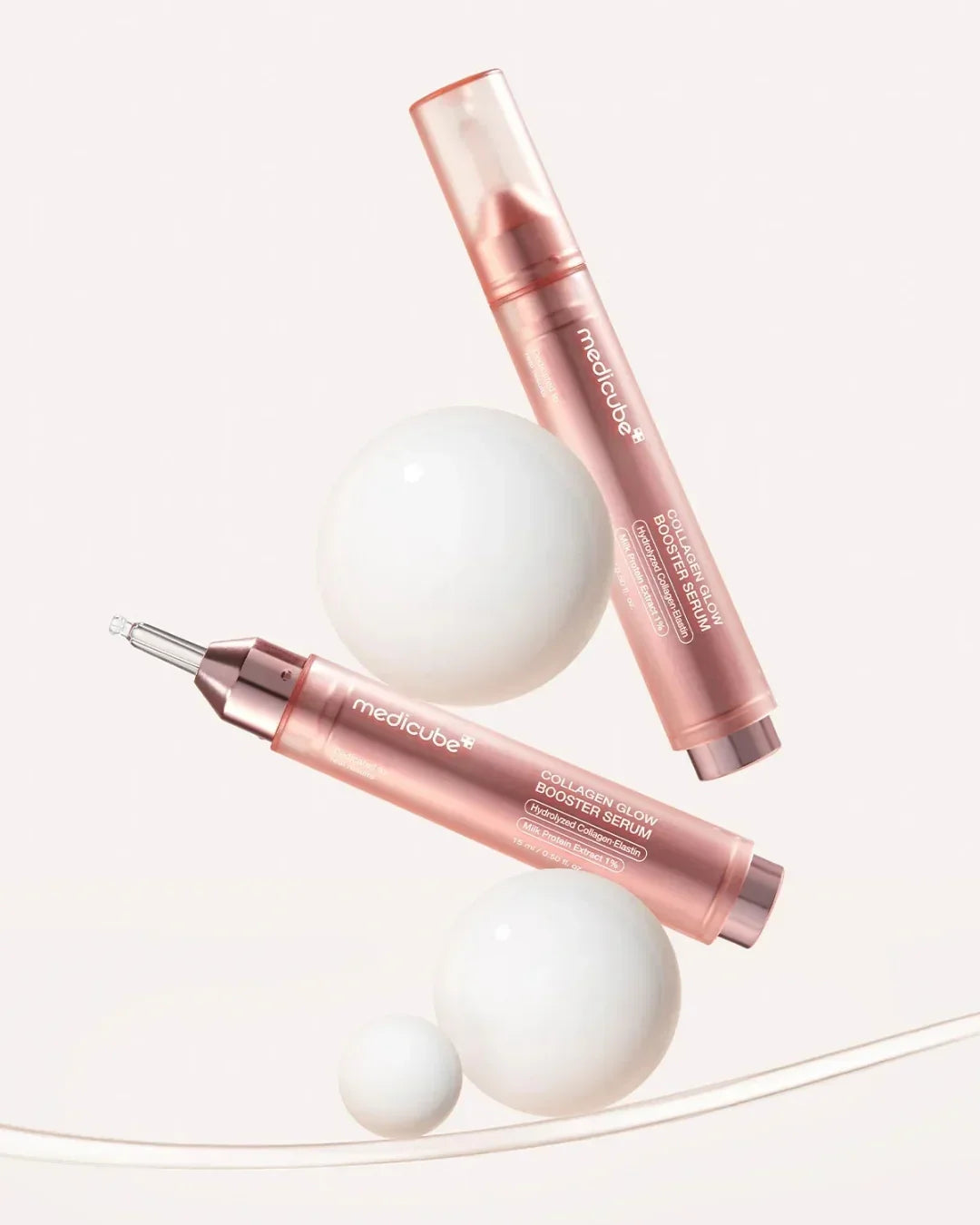 Medicube Collagen Glow Booster Serum 15ml in rose gold packaging with white spheres on pale background