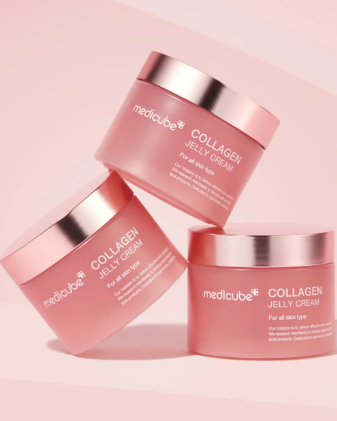 Three pink Medicube Collagen Jelly Cream jars with metallic lids on a soft pink background