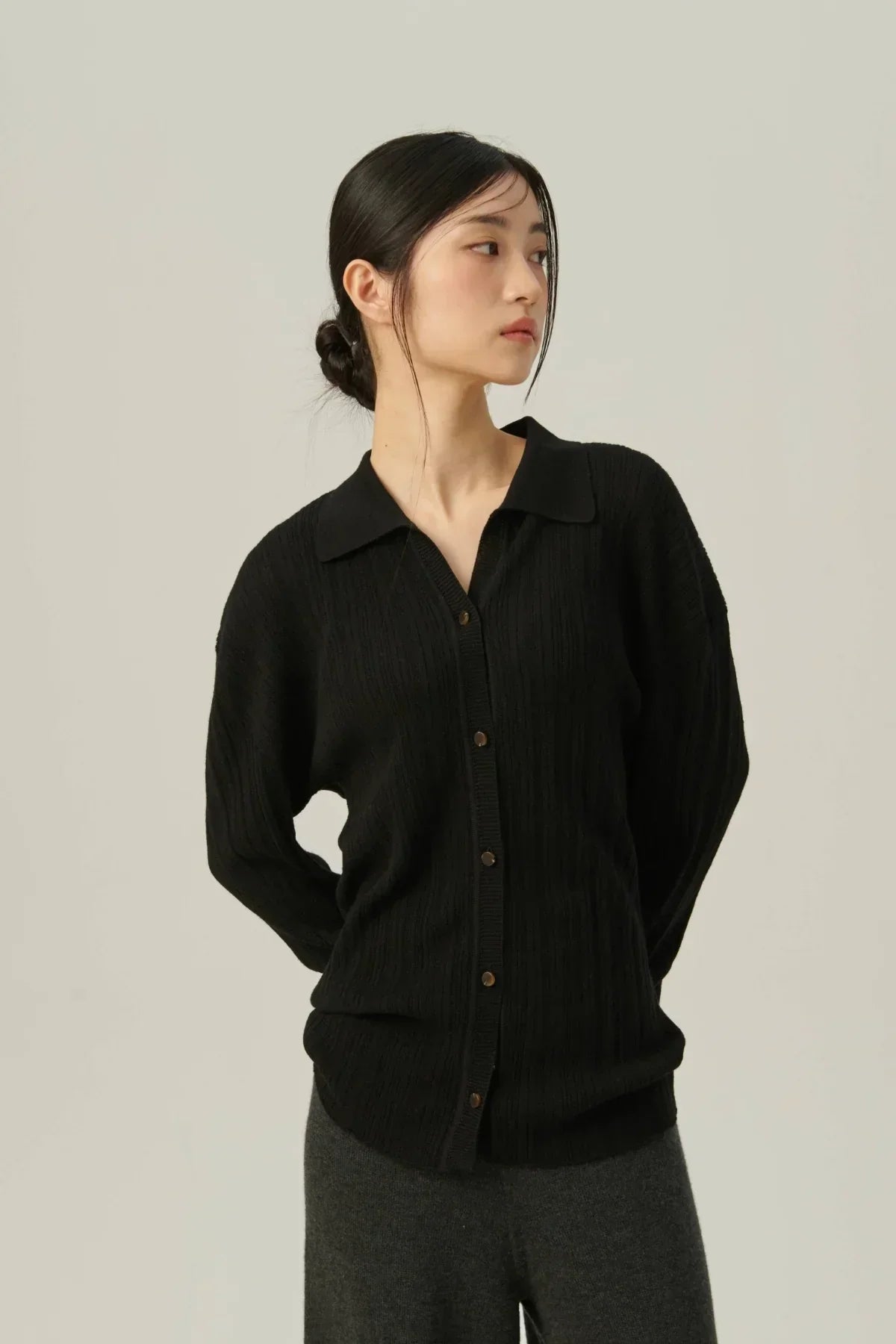 Asian woman wearing black collared rib knit cardigan with buttons, posing against neutral background