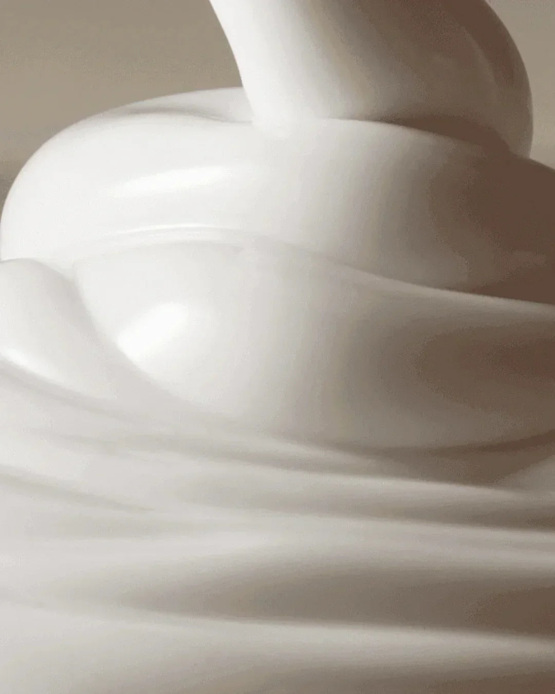Close-up of smooth, creamy white sunscreen lotion swirled in soft peaks with glossy texture
