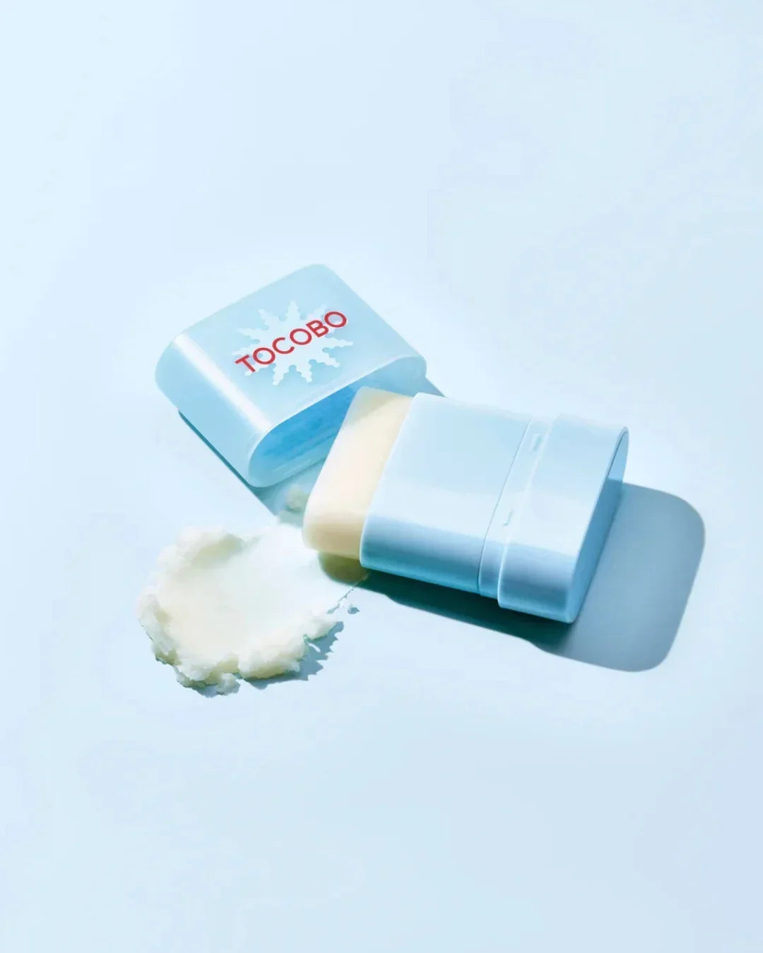 Open TOCOBO sunscreen stick with white cream and blue packaging on light background