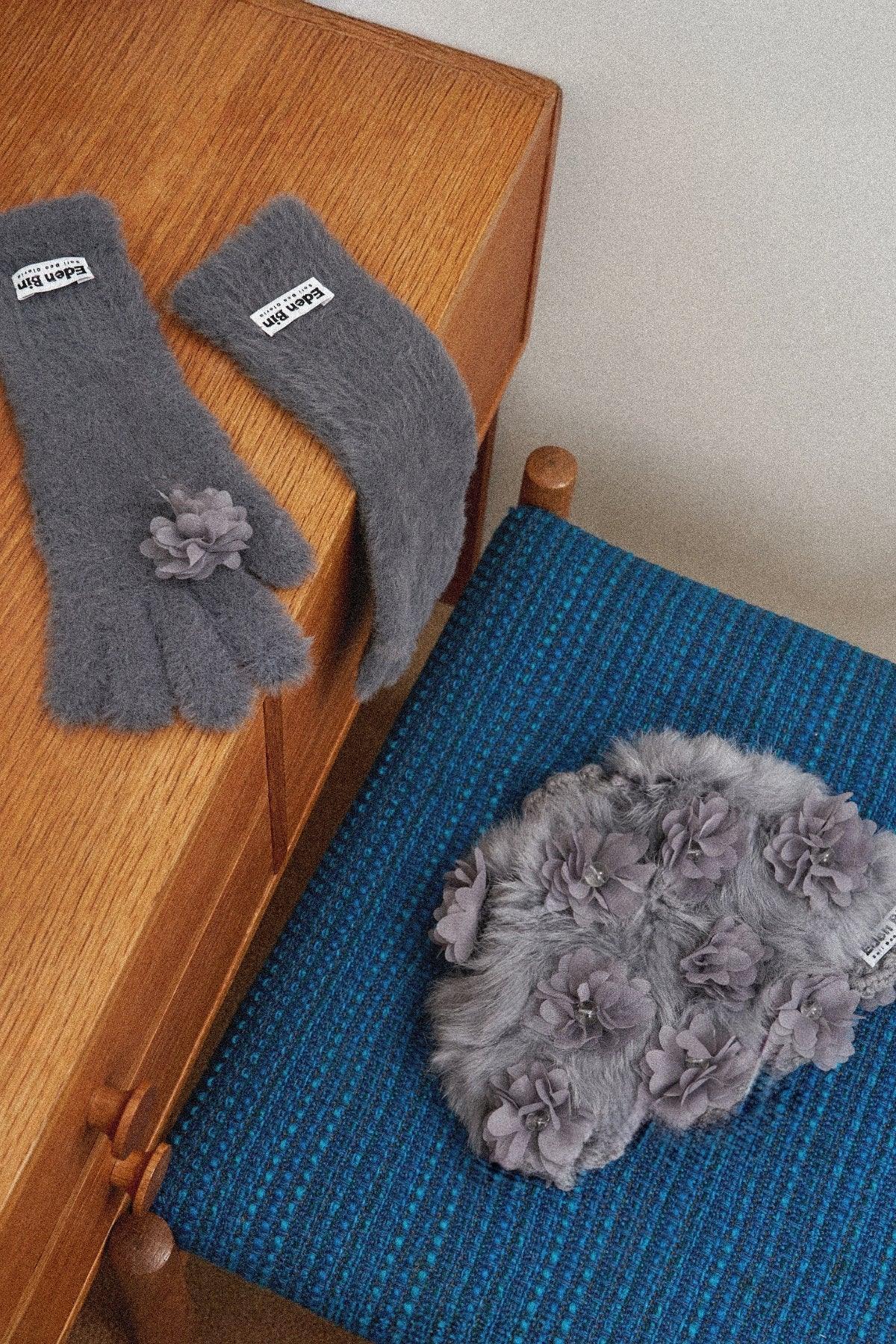 Grey mink fur gloves with flower applique on wooden drawer and matching fur beanie on blue chair
