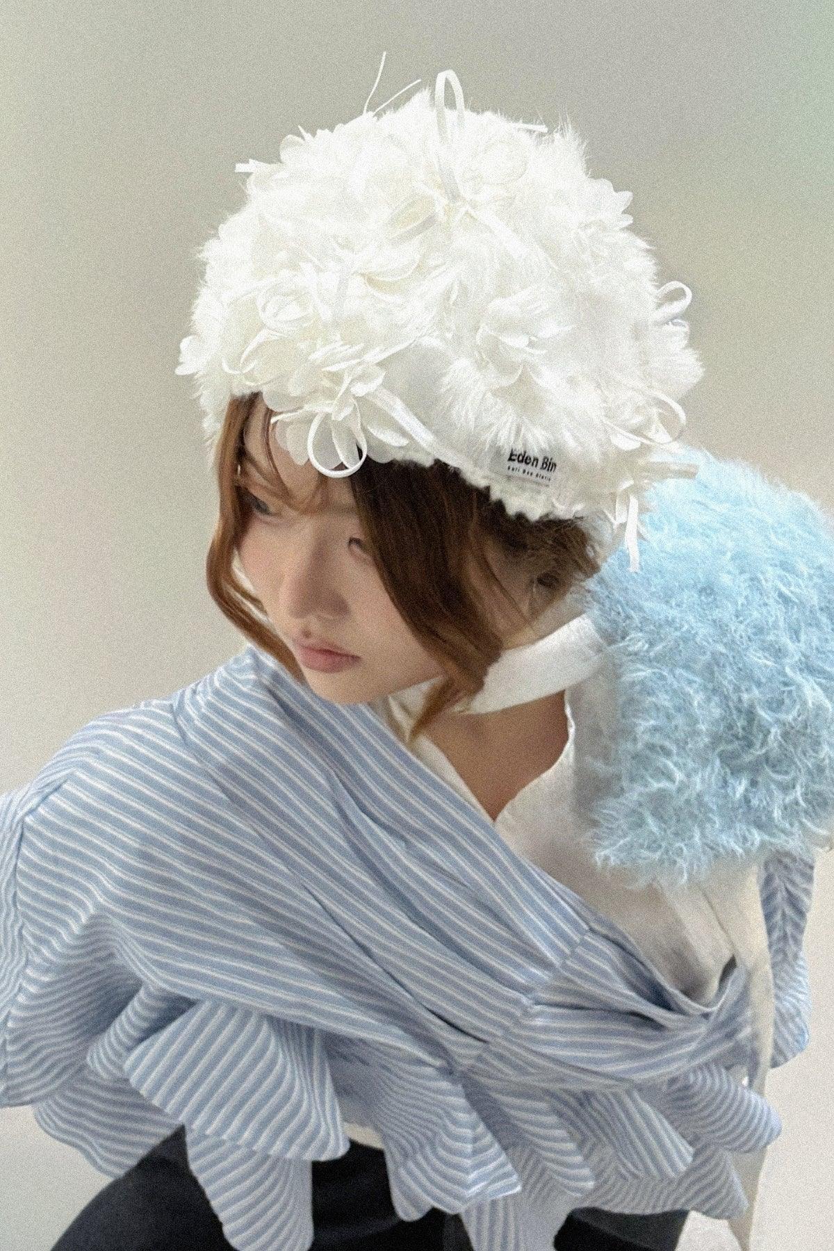 Woman wearing a white couture flower applique mink fur crochet beanie and a light blue striped ruffled garment