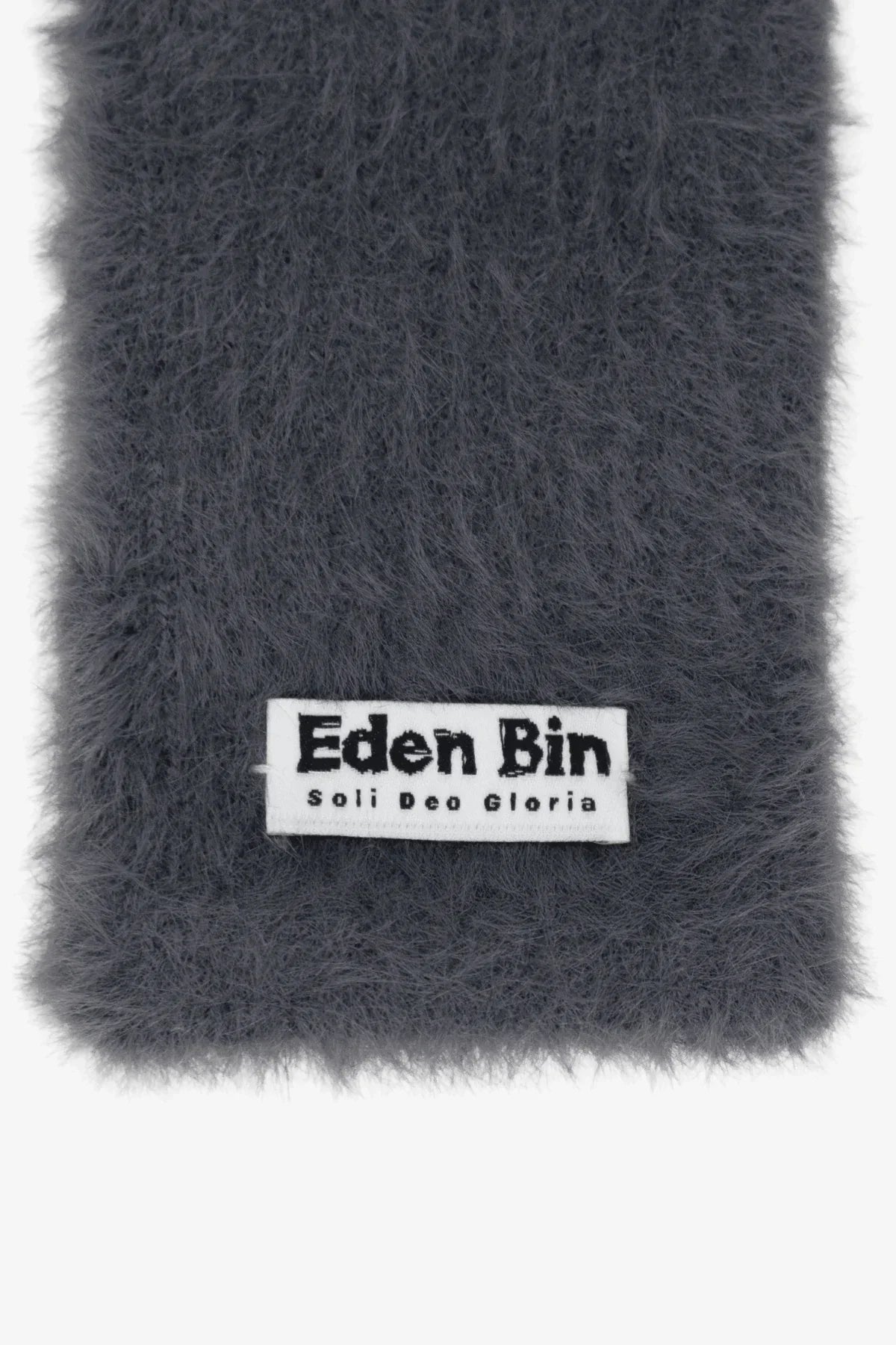 Close-up of grey fuzzy fabric with white label reading Eden Bin Soli Deo Gloria
