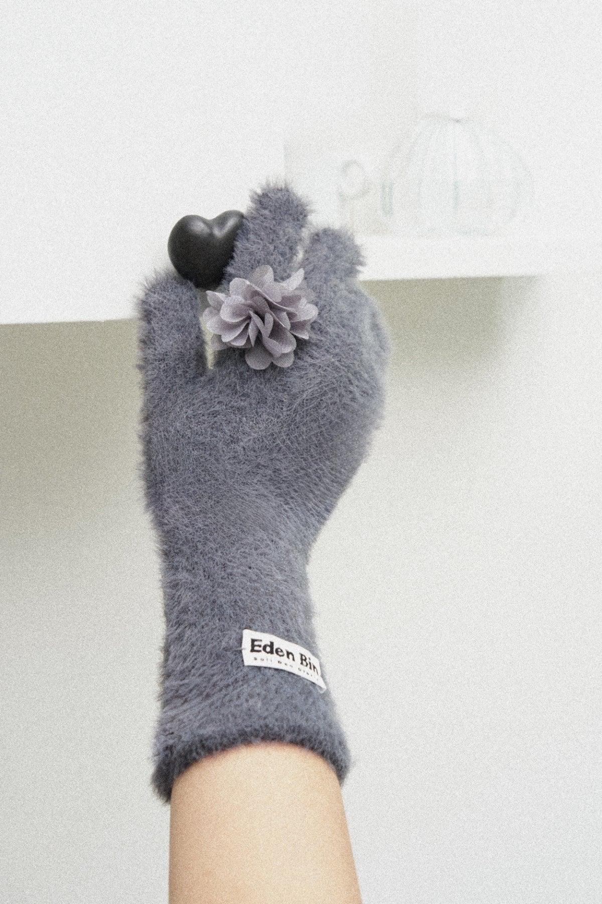 Grey fluffy ring gloves with flower applique and Eden Bin label holding a black heart object