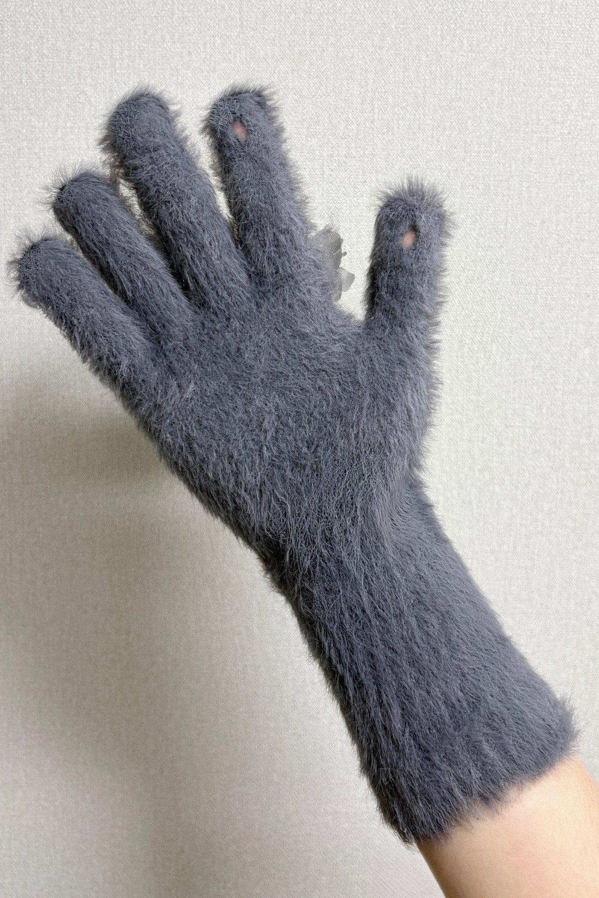 Hand wearing fuzzy grey gloves with ring and floral applique detail on inner wrist