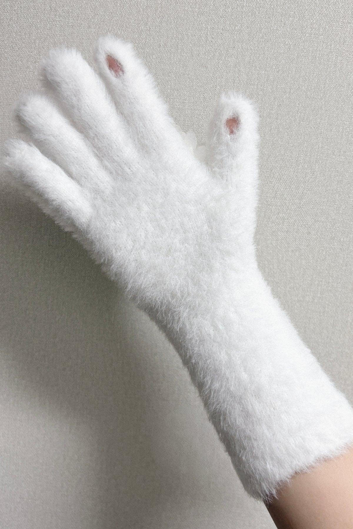White fuzzy soft knit glove on hand with open fingertips against neutral background