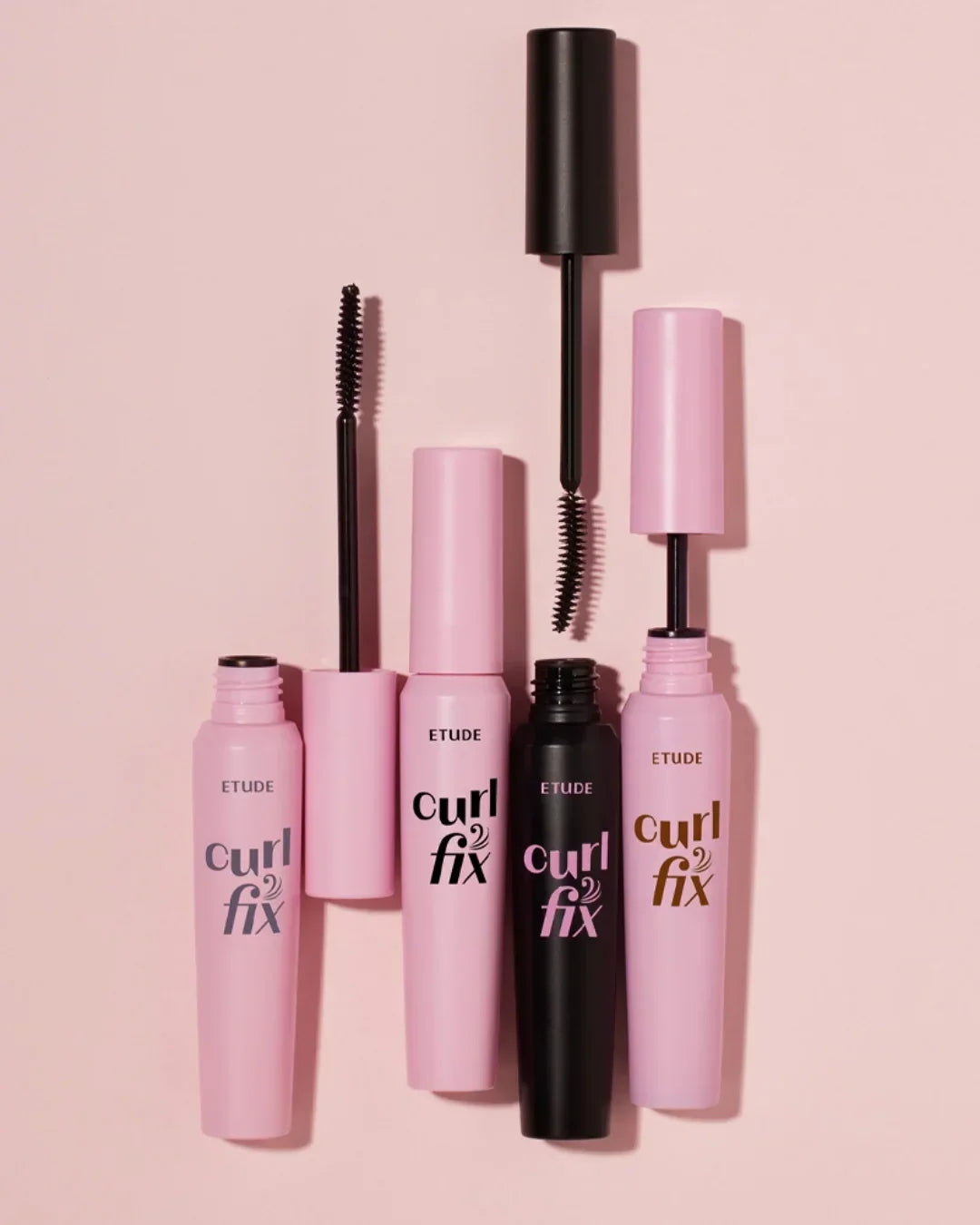Etude Curl Fix mascara lineup with pink and black tubes and curved brushes on light pink background