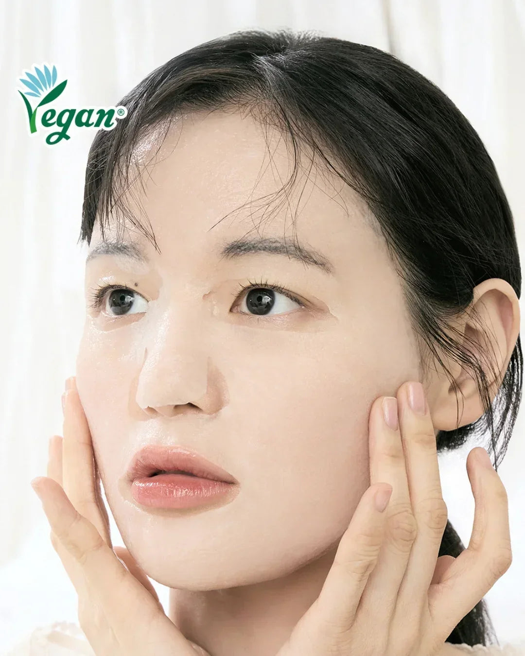Close-up of woman with glossy vegan facial mask gently touching her face, clear skin focus