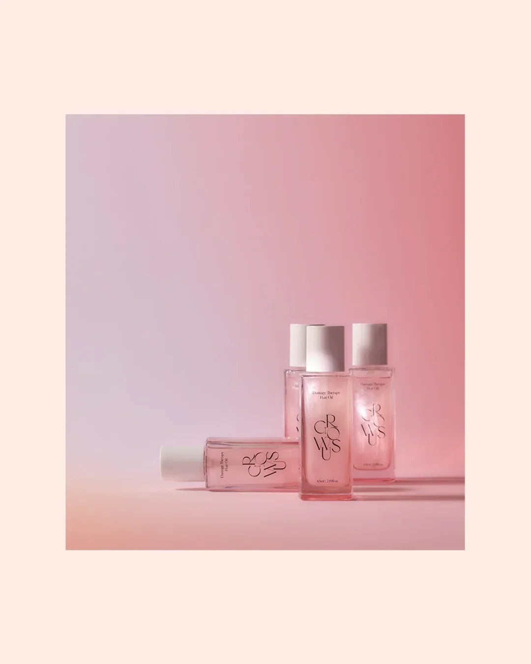 Four pink bottles of GROWSUS Damage Therapy Hair Oil against a soft pink gradient background